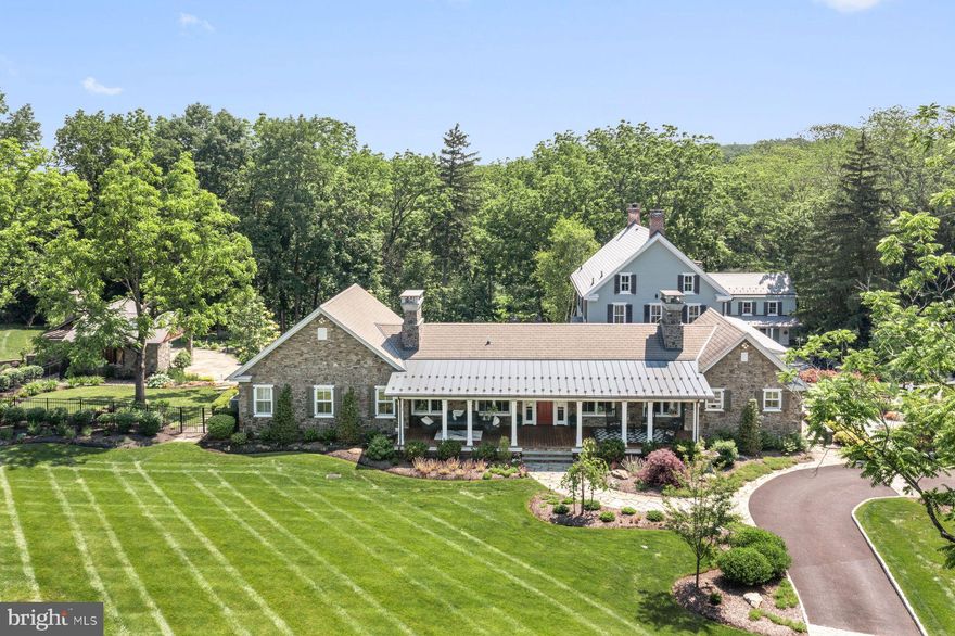 Tucked amid 12.7 private acres in picturesque Bedminster Township, this exceptional estate tells a uniquely American story—steeped in Bucks County history and elevated for modern living. Centered on a restored c.1840 brick Colonial farmhouse and its companion, the charming c.1763 settler’s cottage, the property is listed in the township’s Historic Resources Inventory. An original William Allen land grant to David Culp, a German Mennonite settler, the original structures have been expanded and reimagined to reflect the best of contemporary design and smart-home innovation—all while honoring their historic roots. At the home’s heart is a 2011 sun-filled stone addition that integrates seamlessly with the original farmhouse. The open plan includes a 2023 gourmet kitchen and butler’s pantry, a vaulted family room with exposed beams and fireplace, library, formal entry, and elegant primary suite wing with private office. Throughout, you’ll find tray and coffered ceilings, reclaimed Philadelphia church hardwood floors, high-end lighting, and exquisite architectural detailing. The columned front porch with gas carriage lanterns sets a stately tone, leading into a welcoming foyer and gallery-style hall. The main-level primary suite is a true retreat with a tray ceiling, Mendota propane fireplace, and French doors to the pool. The luxury en suite bath includes radiant floors, jetted tub, walk-in glass shower, dual vanities, ample storage, and a custom walk-in closet. A pocket-doored office features built-ins, a stone-topped desk, and motorized shades. An elevator connects to the fully finished 2,287 sq ft lower level with media room with 85" screen and surround sound, fitness studio with rubber floor, quartz-counter laundry, and extensive storage. The kitchen will delight any chef: honed marble counters, a large island, 6-burner Wolf range with griddle and double ovens, pot filler, custom hood, Miele steam oven and microwave drawer, and a wall of Sub-Zero refrigeration including wine and beverage units. The butler’s pantry adds more cabinetry, a Miele coffee system, ice maker, and reverse osmosis water system. The dining room, set beneath a coffered ceiling, opens via wide sliders to a covered porch overlooking the lush courtyard with koi pond, waterfall with bridge, and whimsical life-sized chessboard. The formal living room, just inside the 1840s double entry doors, features a fireplace and gracious proportions, ideal for music or conversation. Upstairs are three beautifully appointed en suite bedrooms, each with radiant-heated floors, glass walk-in showers, and smart bidet toilets; one includes a claw-foot tub.  A fifth bedroom suite is on the lower level, and features a private entrance with covered porch. Just steps away, the cottage—renovated and with its own address (9A Blueberry Lane)—offers 785 sq ft of charming living space. A vaulted bedroom, full bath with rustic finishes, kitchen/living combo, and rear deck overlooking Deep Run creek make it ideal for multi-generational living, or guest or rental home. The resort-style grounds are designed for entertaining. A multi-level flagstone patio with gardens and propane firepit surrounds the heated saline infinity-edge pool and spa, anchored by a stone cabana with wood-burning fireplace, grilling kitchen, dining area, and a full bath with open-sky river-stone shower. A heated greenhouse provides a space for creativity and calm. Modern upgrades include a whole-house generator, EV charging station, solar array, app-controlled irrigation system, and multi-zone high-efficiency HVAC with smart thermostats and on-demand hot water. Located just 15 min. from Doylestown, under an hour from Philadelphia, and two hours to NYC, this is an exceptional opportunity to own a timeless country estate with every modern convenience. Whether as a full-time residence or a high-end retreat, this property is the embodiment of architectural excellence, smart living, and rural elegance.