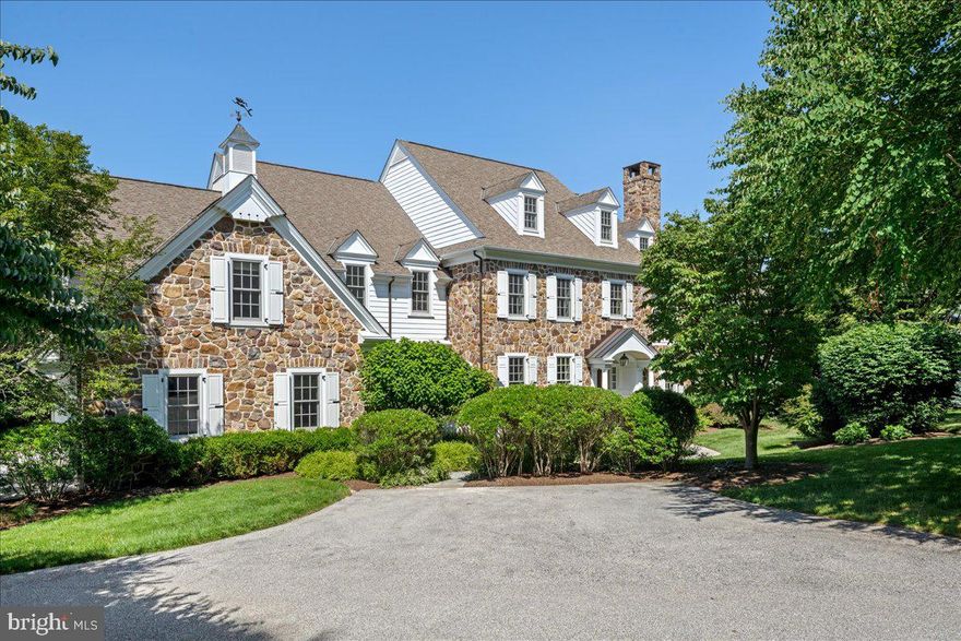 Tucked into the highly desirable Fenimore community in Gladwyne, this classic stone colonial—Built by Pohlig Builders, long respected for their superior craftsmanship and thoughtful design—offers timeless elegance and exceptional functionality. Set on Summerhill, a quiet cul-de-sac within the community that hosts just three additional homes, the property enjoys a private setting and access to the neighborhood’s open green space at the end of the street.
Finished across four beautifully executed levels, this home is designed to support both daily life and large-scale entertaining, balancing formal architecture with comfortable family living. A traditional center hall layout welcomes you with a gracious foyer flanked by a fireside living room on the right and a formal dining room on the left. Rich hardwood floors run throughout the main level, and the dining room connects seamlessly to a stylish butler’s pantry—open in design to lend a sense of flow between serving and gathering spaces.
The kitchen is expansive and light-filled, anchored by a large, seated island and appointed with high-end appliances. A charming breakfast room, wrapped in windows, opens to one of two stone terraces—this one outfitted with a built-in grill and generous seating area overlooking the mature rear landscape and century-old tree line. The kitchen flows into a large family room where a vaulted ceiling adds volume and natural light. A wood-burning fireplace, flanked by windows and custom built-ins, centers the space with warmth and architectural presence.
The mudroom wing provides a secondary entrance with utility and elegance—complete with a potting sink, a discreet home command center for managing household needs, and one of two powder rooms. This area also includes access to the oversized three-car garage. A richly paneled library sits just beyond the living room, offering a quiet retreat or sophisticated entertaining space with views of the rear grounds.
Upstairs, the primary suite is an airy, serene retreat. A vaulted ceiling adds light and dimension, while his-and-hers walk-in closets and a spacious dressing area lead to a well-appointed bath featuring dual vanities, a soaking tub tucked under a window with custom shelving, a separate seated shower, and private water closet. In addition to the primary suite, there are five family bedrooms on this level. One offers a private en suite bath and walk-in closet. Two bedrooms are joined by a Jack and Jill bath, while the remaining two share a thoughtfully designed connecting bath. All bedrooms are generously sized with either walk-in or double closets. A large laundry room completes this level with added convenience
A secondary staircase leads to the third level, where a bright office, large walk-in closet, and extensive storage await.
The finished lower level offers multiple areas for recreation and relaxation, including a fitness room, wine cellar, billiards space, TV lounge, and a full bath. Natural light filters in, enhancing the livability of the space.
Tucked just off the family room is a second, more secluded stone terrace—a hidden garden room of sorts. Surrounded by stone walls for privacy and shaded by a pergola with mature climbing vines, this intimate space is centered by a stunning outdoor fireplace—an ideal spot for quiet conversation or evening gatherings.
A rare offering in one of Gladwyne’s most sought-after neighborhoods, this home is at once refined and relaxed, grounded in classic design yet thoughtfully expanded for modern life.