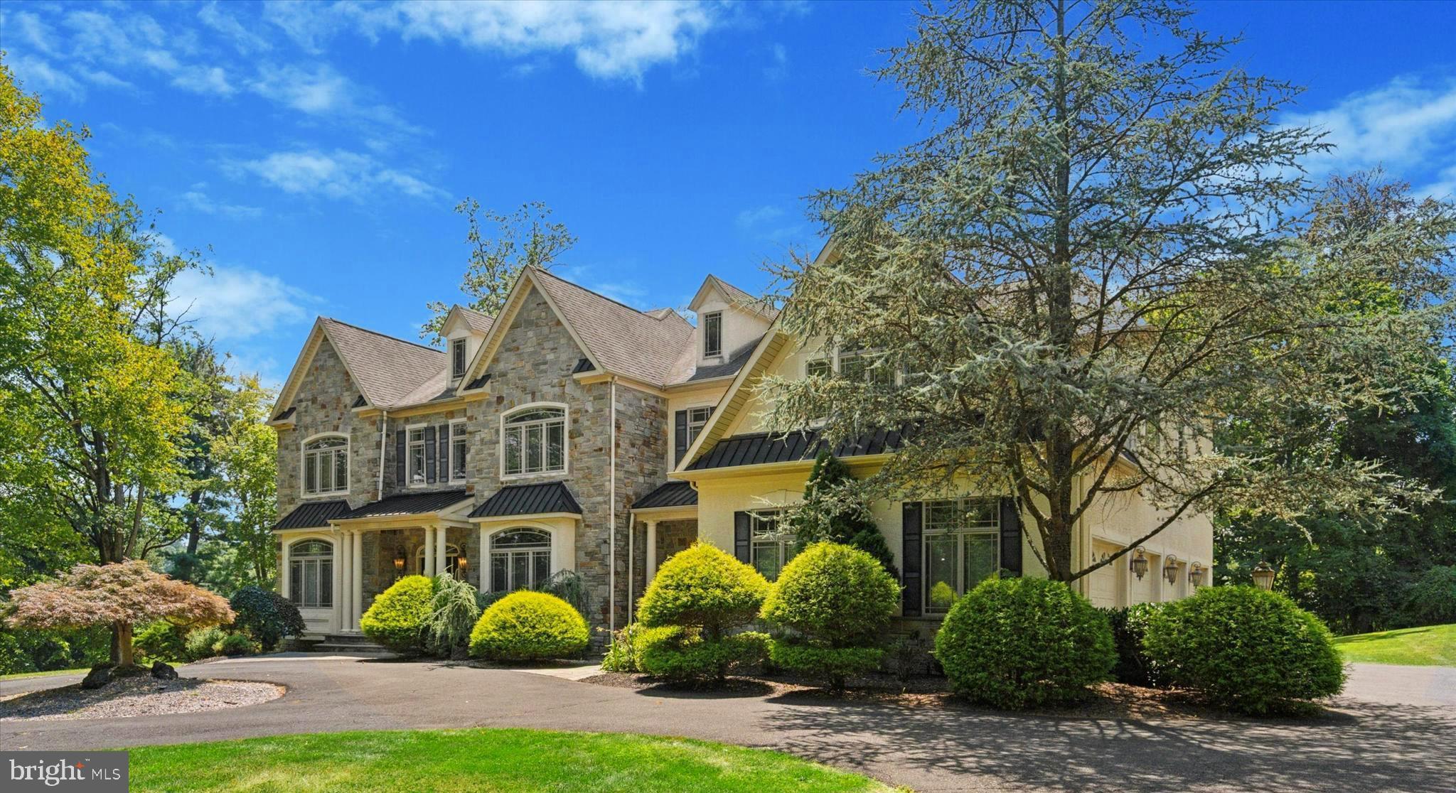 1514 CHERRY LANE in the prestigious enclave of Rydal, Pennsylvania, is an architectural masterpiece that combines timeless elegance with modern luxury. Set on a beautifully landscaped 1.27 acre lot, this grand colonial residence offers approximately 8,589 square feet of exquisitely finished living space, designed to impress at every turn. From the moment you arrive, the stately façade, distinguished rooflines, and manicured grounds set the tone for the refined living experience within. A sweeping driveway and expansive 4-car attached garage provide a graceful approach, while the property’s mature trees and lush greenery ensure both beauty and privacy.
Inside, the home’s soaring ceilings, oversized windows, and thoughtfully crafted architectural details create an atmosphere of grandeur and light. The formal entryway opens to expansive living and entertaining spaces, where gleaming floors, arched passageways, and custom millwork elevate the home’s aesthetic. The dramatic two-story family room serves as a true centerpiece, anchored by a magnificent stone fireplace and a wall of windows that frame picturesque views of the private rear grounds. The gourmet eat-in-kitchen is a chef’s dream, featuring a two-tiered center island with prep sink, granite countertops, bespoke cabinetry, large pantry and premium appliances, including a Wolf range with pot filler and a built-in refrigerator. A butler’s bar with fine woodwork and wine storage adds a sophisticated touch for hosting gatherings, while the adjoining breakfast room offers an inviting space for everyday dining. A formal dining room with tray ceiling and wainscoting, elegant living room with fireplace, private office, full bath, powder room and convenient mudroom complete the main level.
The upper level offers four generously proportioned bedrooms, including a luxurious primary suite designed as a private retreat. This sanctuary features vaulted ceilings, a spacious sitting area, walk-in closets, and a spa-inspired bathroom with dual vanities, a soaking tub, water closet with bidet and an oversized glass-enclosed shower. Three additional bedrooms are equally refined, each with ample closet space and access to beautifully appointed bathrooms. The convenient laundry room and staircase to full size attic complete this level. The 3000+ square foot fully finished lower level expands the living space with a spacious media/family room, large wet bar, hair salon with sink, an additional bedroom, bonus room, full bath, and direct walk-out access to the rear patio.
Outdoors, the property continues to impress with its multi-level deck and serene, park-like setting. Rolling lawns, landscaped garden beds, and mature trees create a picturesque backdrop for outdoor living. The location offers a perfect balance of seclusion and accessibility—nestled in the quiet charm of Rydal, yet just moments from fine dining, shopping, and cultural attractions. The nearby Rydal SEPTA station ensures an easy commute to Center City Philadelphia, while the highly regarded Abington School District adds further appeal. A rare offering of scale, sophistication, and craftsmanship, 1514 Cherry Lane stands as one of Rydal’s most distinguished residences—ideal for the discerning buyer seeking a home of exceptional presence and enduring value.