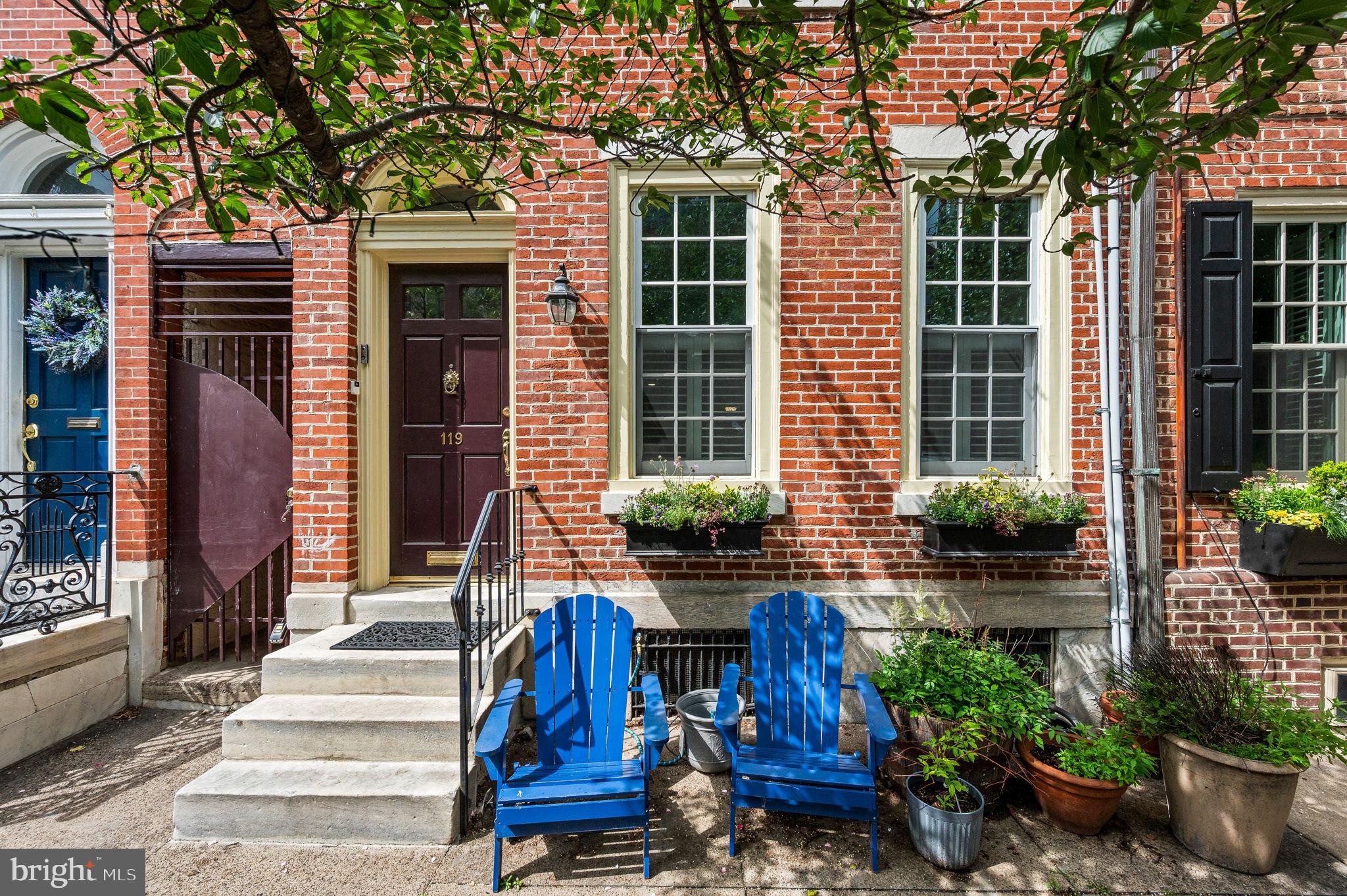 Nestled on a tree-lined block in one of Philadelphia’s most cherished historic neighborhoods, this brick beauty weaves together architectural charm and everyday comfort with effortless grace. From the moment you step through the foyer’s rounded transom entry, you’re greeted by inlaid wood floors, warm gas fireplace, and a sense that this home has stories to tell. Built-in bookshelves frame a picture window that gazes out to a private patio—an ideal perch for lazy Sundays with a novel and morning coffee. The separate dining room, with a bay window, offers space for holiday celebrations and quiet dinners alike.
The light-filled galley kitchen is a cook’s delight, outfitted with stainless steel appliances including an induction stove with dual ovens and a microwave-convection combo. A cleverly designed mudroom/office connects the kitchen to a powder room, pantry, coat closet, and leads to the patio—with a private alley and a staircase to a second-floor deck. Upstairs, three en-suite bedrooms provide comfort and flexibility. The primary suite overlooks quaint Kenilworth Street and offers rare city luxury: four customized closets, including a walk-in. The second bedroom, currently a spacious office/den, features laundry in the bath and direct access to a sun-drenched deck—perfect for a potted garden or evening retreat. Discover a showstopper on the 3rd floor: a vaulted-ceiling bedroom with a magical loft accessed by a trinity-style stair, ideal for a reading nook, creative space, or a child’s dream hideaway. Don’t miss the Tiffany blue ceiling and stained-glass windows that lead you up to a private roof deck with skyline views. A finished basement with wood-look tile flooring adds bonus space for a playroom, home gym, or extra storage. Whether you’re drawn to the preserved historic touches or the modern conveniences tucked into every corner, this one-of-a-kind residence is a rare find—inviting you to write the next chapter in its long Philadelphia story.