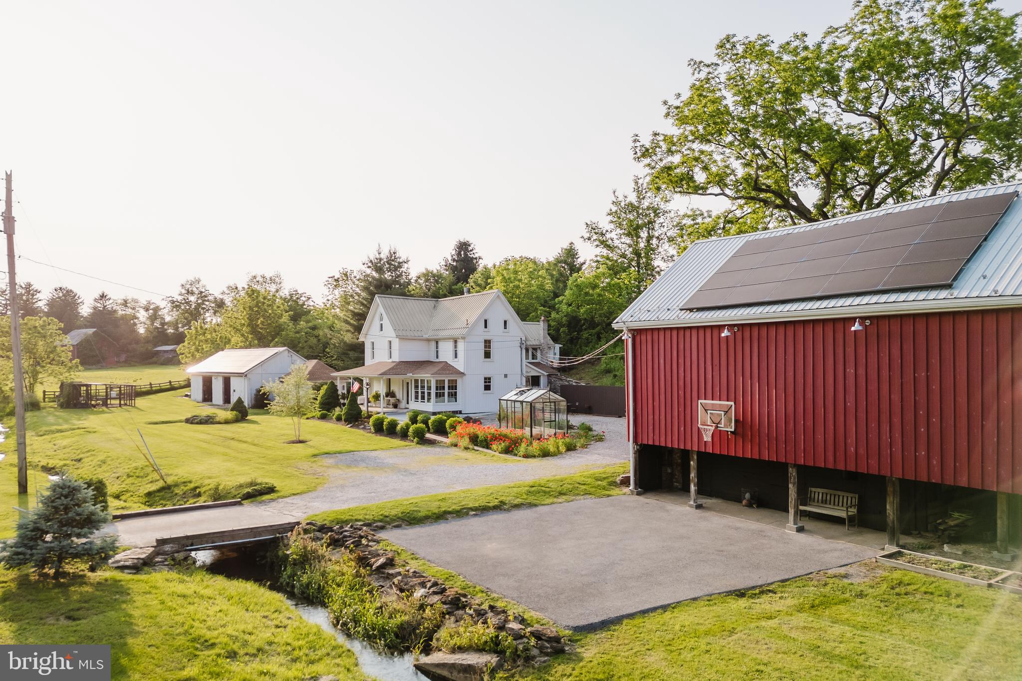 BACK ON MARKET THROUGH NO FAULT OF THE SELLERS - BUYER'S FINANCING FELL THROUGH! This quintessential 1800s Farmhouse has been reimagined with flourishing Peony Fields & a Spectacular Entertainer’s Barn. Escape to this rare and enchanting 8.38 acre farm, where pastoral charm meets modern living. offering 6 tillable acres blooming annually with vibrant peonies - perfect for a flourishing flower business, hobby farming, private retreat, or unforgettable gatherings . At its heart stands a meticulously remodeled 1800s farmhouse that seamlessly blends historic character with today’s modern luxuries. Step into a welcoming sun porch and into the kitchen, as you do on a farm, and you will find a home filled with warmth, and probably something yummy and fresh cooking. The eat-in kitchen is a showstopper, featuring exposed brick, marble countertops, and reclaimed hardwood floors older than the house itself. A premium dual-fuel Wolf range with double ovens, griddle, grill, and custom hood anchors the space. Enjoy the charm of original wood banisters and wood-burning fireplace. Upstairs be charmed by the exposed original flooring. The primary suite includes a spa-inspired ensuite with a glass-surround shower, marble floors, classic tile, and generous storage. Three additional bedrooms and a second full bath with marble countertops complete this level. The finished attic on the third floor adds two versatile rooms—currently serving as an office and sewing studio. The rustic yet practical mudroom/laundry room on the main level offers exceptional utility with charm to spare. Beyond the home, an array of thoughtfully preserved outbuildings offer boundless versatility. The centerpiece is the fully renovated, climate-controlled, entertainment barn! Warm and welcoming space for any event or family gathering with vaulted ceilings, exposed beams, stunning details, and hardwood floors. All you can imagine with a billiards loft, full bar with a farmhouse sink, full-size refrigerator, ice-maker, beverage fridge, kegerator, dishwasher, microwave, pantry and custom cabinetry, wine rack, and TV. Spacious and open with a pellet stove, three ceiling fans and full bathroom add both function and style. Step out to a Deck and gravel patio with fire pit—ideal for gatherings large or small. Additional charm includes a quaint bridge over a babbling brook, a glass greenhouse, Chicken coop, and a lush garden area where the family sits to complete their day and watch the sunset. And there is MORE! The Old horse barn with hayloft and lean-to is currently being used as a 2 car garage. The Historic butcher and smokehouse now functioning as a spring house where fresh spring-fed water supplies the homestead. And no farm would be complete without a 48x24 block barn for tractor storage, workshop, or creative use. This extraordinary property is a rare blend of timeless craftsmanship, pastoral beauty, and modern luxury. Tranquility—a one-of-a-kind sanctuary where every structure, stone, and beam tells a story. Perfect for those dreaming of a gentleman’s farm, peaceful homestead, boutique flower business, or a charming event destination, this is country living at its most refined and romantic.