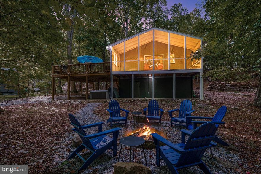 This spacious, newly-renovated two-bedroom cabin features a large screened-in porch overlooking a spacious backyard. Inside, you’ll find chevron-pattern vinyl plank flooring, vaulted ceilings, and a cozy brick wood-burning fireplace. The open layout connects the living, dining, and kitchen areas. The U-shaped kitchen includes a bar with seating and plenty of counter space. A large deck offers built-in seating with room for more, and below is a covered patio with a concrete floor.  Other highlights include a full bath, central HVAC, and WiFi internet.  The cabin is located in the Sleepy Hollow community, with access to a small private lake and beach – and only about 20 minutes from downtown Berkeley Springs.  Seller spent over $46,000 renovating & furnishing the property.  As a vacation rental it has generated $117,000 over the past 34 months, and can come with an existing property manager and cleaner. Furniture & hot tub optional, available for purchase.  See seller docs for a summary of rental history and financials.  $1,000 buyer credit if you continue using the same property manager.  Perfect primary or vacation home!