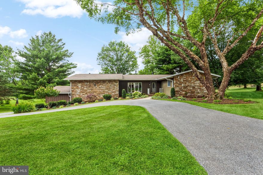 Sure To Catch Your Eye!  This stunning home, highlighted by stacked stone, is surrounded by mature trees and luscious landscaping, has a convenient circular driveway for guests and a separate driveway to access the 3-bay garage for the owners.  Once inside you will be impressed with the uniqueness offered by the floor plan.  Step from the foyer into the sunlit dining room featuring towering cathedral ceilings and a cozy fireplace.  Beyond is an opulent kitchen with an spacious open sitting area, followed by a cheerful Sun Room, and then onto an enormous family room where the entire household gathers in the evenings and weekends.  This room also has its very own HVAC system and wood stove for chilly nights.  To complete the main level, there are three bedrooms and two luxurious baths; the primary bath has warm heated floors!  On the lower level, there is a den/theatre room/man cave, dependent upon your desires, with wet bar and bar refrigerator.  In addition, there is an in-law apartment featuring living room, kitchen, bedroom, bath and its own separate laundry room.  There is plenty of natural light, a walk out slider to a rear patio and it has a separate electric meter, too.  Additional features are:  1 of the bays of the garage is tall and can accommodate an RV or similar vehicle, workshop area below the rear deck, 6 solar panels which lowers electric costs substantially, 3 hot water heaters: one to service the main level, one for the in-law apartment and the last handles the heated floors for the primary bath.  This home has it all, so act now before it’s too late!
