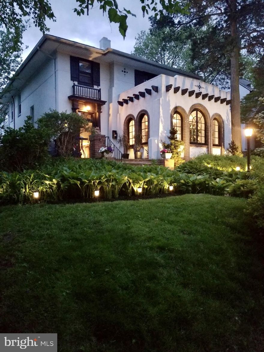 This meticulous 1920s Spanish Colonial is a prime example of the historic architecture found on the 600 block of Elkins Avenue.  Nestled within a tranquil pocket in Elkins Park, the area features mature trees and Spanish, Dutch and English period home designs. The residence is perfectly positioned just three blocks from the Elkins Park Train Station, offering seamless access to the city alongside a charming village-like walkable atmosphere of downtown Elkins Park. The home’s original details such as inset stucco tiles, exposed rafter tails, curved walls, hardwood floors and a magnificent solid-wood entry door flanked by half-round columns adds to the charm and appeal. The interior is marked by a full-width living room with a gorgeous plaster and brick, wood-burning fireplace with arched face. The custom built-in bookcases lead into a breathtaking sunroom/office surrounded by triple-arched casement windows. This is a perfect working environment and area for raising your botanical treasures. Next, enter the formal dining room, which has plenty of space for entertaining, leading to the sophisticated chef’s kitchen featuring custom cabinetry, quartz surfaces, a herringbone subway tile backsplash, and a professional-grade pot-filler. There is a large breakfast bar and an eating area off to the side with plenty of table space. This space flows effortlessly into a dramatic, two-story sunken family room, where a second stone-surround fireplace and soaring custom built-ins create an atmosphere for gathering family and friends.  There is convenient entry access and closet from the new driveway and detached 2 car garage with electric. Additional amenities, include a coffee bar and a  first-floor laundry to further elevate the home’s function. The second floor is dedicated to rest and relaxation, consisting of a spacious primary suite. This lovely retreat offers generous built-ins, closets, a modern updated bath with a shower stall, and French doors that open onto a roof deck. An additional three bedrooms, an updated modern hall bath, and a unique loft office with a custom wrought-iron railing overlooking the family room complete the upper level.  It has eco-conscious solar panels and central A/C that services the 2nd floor. The lower level is recently updated with new carpet and updated paneling for an additional play room, entertainment or living space. There are two large storage spaces and a utility area with a 2025 boiler and hot water heater. There is a convenient updated outside exit to the side of the home for easy access to the lower level from the outside. This meticulously maintained home offers a sophisticated, yet comfortable lifestyle for the most discerning buyer. Multiple patio areas and a level back yard are perfect for relaxing and entertaining. The neighborhood is rich in green space, offering diverse recreational activities within walking distance. High School Park: Located just 0.1 miles away, this 11-acre natural escape features a meadow, walking trails, and a large playground. Richard Wall Park: A short walk from the home, this park offers basketball and tennis courts, a skate park, and a historic museum. Curtis Arboretum: A stunning 47-acre property with rolling hills, two ponds, and two dedicated dog parks—a premier local spot for quiet reflection. Public transportation including the Elkins Park Train and other train stations are within walking distance or a short commute.