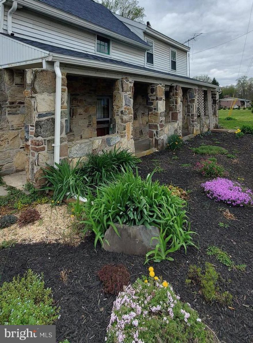 SELLER replacing house sections of roof with shingles that carry a 50 year transferrable warranty, garage roof to be repaired and recoated, attic rafters to be repaired, flashing to be repaired! Welcome to your charming cottage, a delightful blend of historic character with some modern updates, nestled on a serene 2.15-ACRE LOT in a picturesque rural setting. The stone front with a covered porch adds to the charm! Under the siding are said to be the log walls of the original 2 story structure! Built in the 1860's, this detached home boasts a warm and inviting atmosphere, perfect for creating lasting memories. Step inside to discover a cozy interior featuring a large combination kitchen and dining area designed for both functionality and comfort, ideal for casual meals or entertaining friends. Plenty of room to add an island! A spacious living room with a gorgeous wood ceiling, laundry/mud room and a full bathroom with a tub shower complete the first floor. The second floor has 2 large bedrooms and a huge walk in closet. Outside, the property has a partly wooded backdrop. The level, cleared yard is perfect for outdoor activities. There is a sand pad for your above ground pool.  An outbuilding provides additional storage. Parking is a breeze with ample off-street spaces, ensuring you and your guests have plenty of room to park.  The ceiling in the kitchen/dining area is low. Home being sold "As Is". This Home is located in a rural area but is close to the road. 14 Minutes to Gettysburg, 35 minutes to Harrisburg and less than 3 minutes to Route 15. Embrace the charm and comfort of this unique property—your dream home awaits!