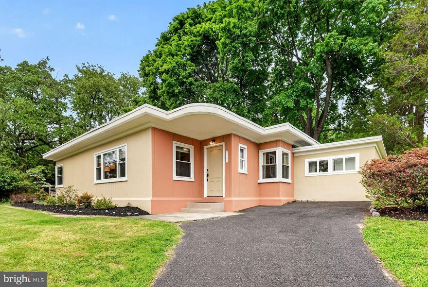 This mid-century modern gem in the highly sought-after Wyndmoor community offers an exceptional opportunity for the discerning buyer. A welcoming foyer introduces a chic, well-appointed interior that has been meticulously maintained and thoughtfully updated. The living room features a coffered ceiling and a triple window that floods the space with natural light. This area flows seamlessly into the dining room, which boasts a corner window, built-in cabinetry, and space for family dining. A sliding door provides easy access to the covered patio. The kitchen serves as a true focal point, featuring nice cabinetry with integrated shelving for cookbooks, an appliance garage, a farmhouse sink, and granite countertops complemented by a tile backsplash. New Stainless steel appliances and a pantry closet complete this space. The versatile floor plan includes a private bedroom tucked away on one side of the home offering an ideal setup for guests or a quiet professional workspace. The primary suite is a true retreat with its coffered ceiling, corner windows and the en suite bathroom addition includes tile flooring, a tile stall shower, a heated towel rack, and a transom window. A door leads directly to a private deck and hot tub to the right (and a front-facing deck to the left to watch the world go by over a cup of coffee or glass of wine), allowing for a seamless transition back to the suite. A second  bedroom also has coffered ceiling and enjoys easy access to the updated hall bathroom, which features tile flooring, a soaking tub , a heated towel rack, double sinks, and additional transom windows. The family room is a standout feature offering built in bookshelves/cabinetry, a large picture window with serene views, and a door to the covered patio. This patio connects the dining and family rooms, facilitating an effortless flow for entertaining. The property is surrounded by mature plantings and trees, space for a fire pit, and a flagstone path leading to a small patio area. The pet-friendly fenced side yard includes a deck, well-maintained hot tub, lawn area, and a deer-proof raised-bed cedar garden.  Significant recent improvements provide peace of mind, including a new roof in 2021, a main heater and on-demandhot water heater in 2020, a full bathroom remodel in 2020, new washer and dryer, and a new hot tub cover and motor in 2026. Nearly all windows have been replaced as well. The location is unparalleled, situated just minutes from downtown Wyndmoor. You can enjoy local favorites such as FROOT, Locals Coffee, Stotesbury Pub and Enza, or shop at Captain Andy’s Market. The home is also conveniently located near the Wyndmoor Train Station, local schools (Maybe mention the district?), parks, the library, Chestnut Hill, Route 309, and the PA Turnpike. This stunner is a 12 out of 10 so HURRY!