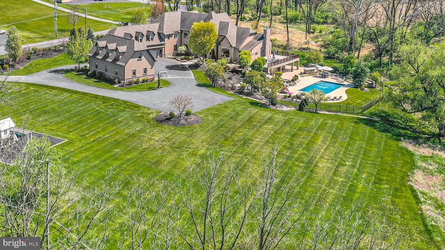 Welcoming…gracious…refined. Hidden Gem is a work of art, showcasing classic architectural elements, world-class materials, modern technology, and superb craftsmanship, nestled quietly in a lovely backdrop with hills and meadows beyond. Custom built  with more than 14,000 square feet of finished living space over 3 levels along with a multitude of outdoor amenities, this is truly a home for all seasons of life.

Inside, each room is bathed with light in a layout that showcases high ceilings, hardwood floors, & plentiful custom built-ins.  The gated entry & circular driveway lead to a 2-story covered porch with stone columns. Double doors open to the foyer, boasting a heated travertine floor, sweeping staircase, 2-story ceiling with custom crystal chandelier, & reclaimed barn beams framing a hand-painted mural by artist R.J. Buckingham. An arched opening leads to the large dining room and 2.5 story great room beyond, with more locally reclaimed beams, a floor-to-ceiling fireplace & custom entertainment center. The gourmet kitchen boasts every appliance required by a master chef, with a plethora of soft-close mahogany cabinets & both honed & river rock granite work surfaces. Nearby, a walk-in pantry is outfitted with matching custom cabinets & counters, while the breakfast room looks out over the private back yard. A large family room provides space for relaxing, while the adjacent satellite kitchen offers additional cooking & prep space. More custom built-ins can be found in the office, and a large 1st fl laundry room includes 2 sets of washers and dryers. A custom designed mudroom includes a walk-in coat closet large enough to accommodate outwear for every season, & leads to the attached 3-car garage. 2 large bedroom suites are on this level as well, each with a walk-in closet and custom en suite bath. Front & back stairs lead to the 2nd floor, with an elevator servicing all 3 levels of the home.

The primary suite features a private balcony, unique ceiling lights & romantic gas fireplace with marble surround. Multiple walk-in closets include custom storage, built-in shoe racks & vanity station. The luxurious private bath includes radiant heated floors, an air-jet tub, glass walled shower &  vanity with dual sinks. 2 more generously sized bedroom suites are on the 2nd floor, each offering a unique aesthetic, with custom en suite baths & walk-in closets. A guest or in-law suite with separate outside entrance offers a full bath, living area & kitchenette.

Visitors will feel as though they have been whisked away to a 5-star resort in the elaborate walkout lower level. A home theater with tiered seating & state of the art projection system offers family night fun, with an adjacent movie theater-style snack counter & kitchenette. The recreation room with radiant heated floor is open to the large wet bar. A full size exercise room is an unexpected amenity, & the adjacent bathroom with steam shower is a perfect post-workout treat. Office space, an additional full bath, & multiple storage rooms are on this level as well. Glass doors lead to the multi-level outdoor space, where a partially covered paver patio includes an outdoor kitchen with built-in gas grill, outdoor speakers, ceiling fans & TV hookup for impromptu dinner parties. The heated in-ground pool has concrete decking & a separate spa surrounded by natural rock features. A koi pond, stone waterfall, and built-in gas fire pit are ideal for whiling away afternoons and evenings in every kind of weather. Along with the 3-car attached garage, there is a separate detached 3-car garage with a fully floored second level, plumbed for heat and a full bath. A whole-house generator brings peace of mind year round.