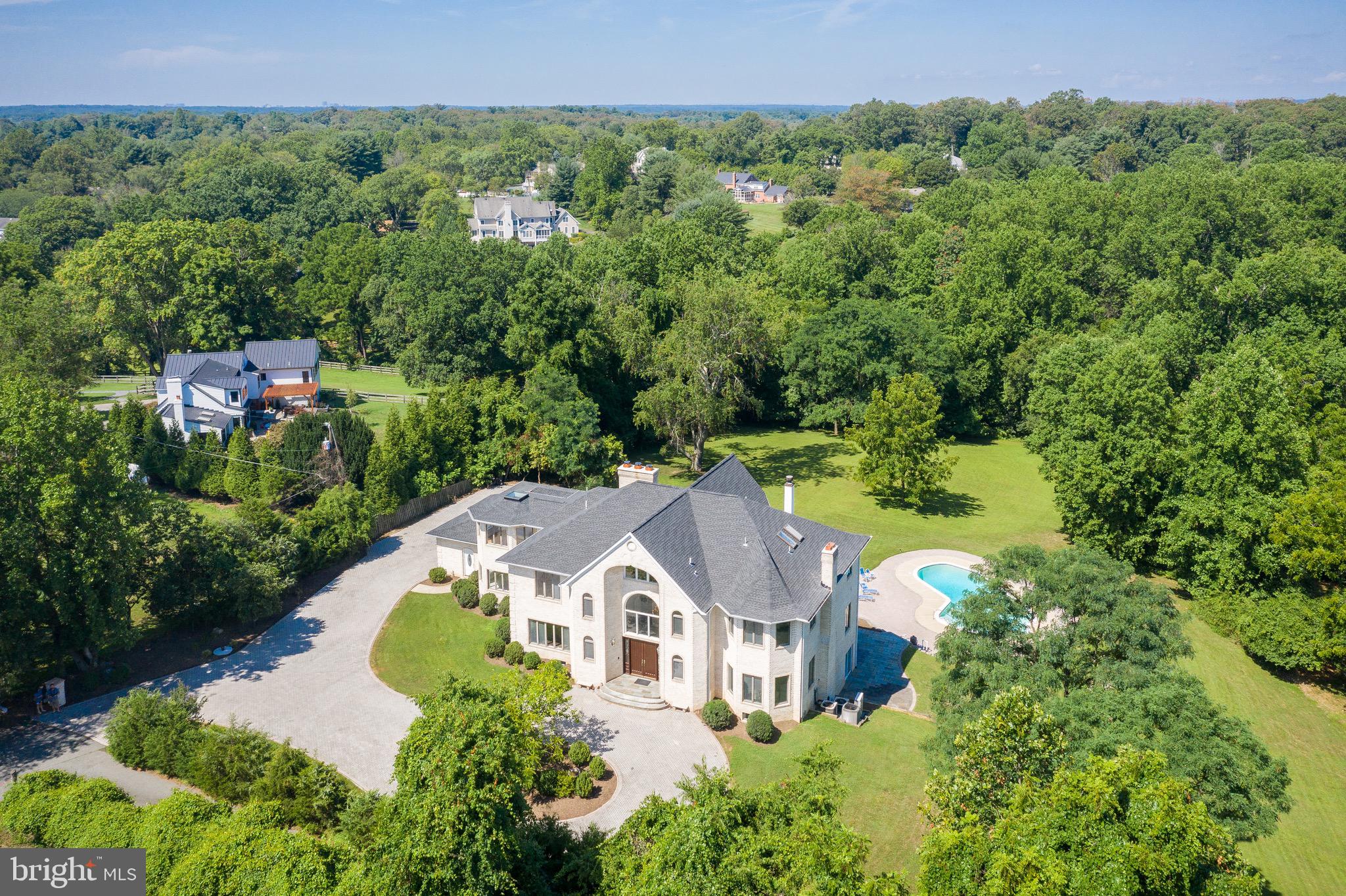 This is a magnificent property on a secluded 3.4-acre lot in the heart of the Potomac countryside, an impressive yet comfortable residence on beautiful private grounds, ideal for multi-generational living, entertaining and business operations in its 4,000 s.f. outbuilding/barn. A circular drive leads to the elegant 11,000 s.f. brick house with cascading lawn leading to the large outdoor pool, fire pit, pond and woods beyond the house. Large rooms in the home bring in natural light and pastoral views, beginning with the impressive marble entry foyer with its stunning chandelier and sweeping front staircase. Grand Living and Dining Rooms flank the foyer, and lead to a Library and Great Room at the heart of the residence. The large Kitchen with center isle, imported granite countertops, stainless appliances, and large Breakfast area, works well for large parties and family living. The two upper levels of the home provide 6 very spacious bedrooms, ensuite baths, bonus rooms and balconies with magnificent views of the property and beyond. The lower level of the house is fully finished and walks out to the terrace, providing a large recreational area with bar, entertaining and workshop space and the 7th bedroom. The large additional brick structure on the property may serve as a barn, onsite office, studio, guest house, basketball or tennis court, business operation or garage; water and electrical hook-up available. Hardwood floors, ironwood decking, lovely trimwork, 5 fireplaces/wood stoves, 5 HVAC systems, a new architectural shingle roof, a massive three-car garage, and many updates by its dedicated owners - all combine to lend quality to this amazing residence.