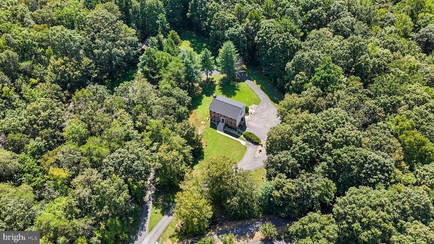 Nature lover’s dream on 7+ private acres! This custom-built home offers the perfect blend of serenity, space, and functionality. A long driveway welcomes you to a beautifully wooded property featuring a creekside screened playhouse with water and electric, a wraparound deck, and your own scenic walking bridge. Inside, the home offers incredible flexibility with 7 bedrooms and 3.5 bathrooms, hardwood flooring, and two fireplaces for cozy evenings. There are so many thoughtful touches on all three levels, the owners have recently replaced the roof in 2021, HVAC in 2018 , freshly painted and updated the kitchen with granite countertops and stainless steel appliances. The property also includes a detached garage with finished office space above—ideal for working from home or a studio—plus a large detached shed for storage or hobbies. If you’ve been searching for acreage, privacy, and a truly unique setting, this beauty is the rare opportunity that checks every box. Great commuter routes into DC, Virginia, and local military bases.