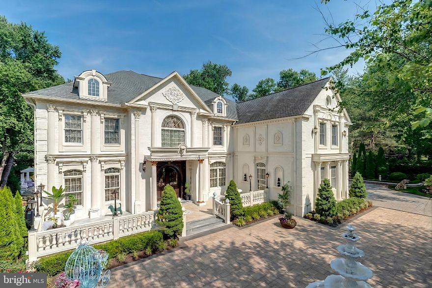 Exquisite artistry, quality craftsmanship, and a touch of glamour combine in this spectacularly appointed 11,000+ sq. ft. manor, set on .89 lush acres. Sited near the Potomac River and moments from the quaint shops and fine dining of Great Falls village, this impressive estate showcases luxurious living at every turn.
A grand marble foyer sets the tone, with lighted recesses, gold-gilded trim, and sweeping views of the home’s richly designed interiors. The formal living and dining rooms feature antique mirrors, crystal chandeliers, intricate ceiling medallions, and decorative hardwood floors with inlaid wool carpeting.
At the heart of the main level, a breathtaking reception area rises two stories, offering an ambiance of elegance and exceptional detail. The richly paneled library is clad in hardwood and features a fossil-stone granite wall with built-ins and fireplace. A coffered-ceiling drawing room includes 11 glass showcases—perfect for art or collectibles. Nearby, a bright music room with bamboo flooring and iron chandelier offers quiet refuge.
The chef-caliber gourmet kitchen impresses with an 8x5 ft. “Louise Blue” granite island and premium appliances. A granite breakfast bar and informal dining area complete the kitchen. Adjacent, a vaulted solarium with bamboo ceiling and French doors opens to expansive decks and lawns, ideal for indoor-outdoor entertaining.
Additional amenities on this level include a paneled elevator, pantry, butler’s pantry with copper sink, mud room, and direct access to the 4-car garage.
Upstairs, the opulent owner’s suite is a private sanctuary that features a tray ceiling, Brazilian cherry flooring with a 100% wool inlay rug, and a cozy sitting area with silk carpet before a marble fireplace and media screen. A morning kitchen offers private refreshment.
The walk-in gallery closet is a boutique experience, with Thomasville cabinetry, center Travertine island, cedar-lined wardrobes, and chandelier-lit tray ceiling. The spa-like primary bath stuns with a central soaking tub before an electric fireplace, dual vanities with 24k gold-gilded sinks, media-screen mirror, and a separate commode room with decorative vanity. Glass-enclosed steam and marble showers, stone seating, and mosaic tilework complete the indulgent space.
Three additional bedroom suites each feature designer bathrooms and walk-in closets. A full laundry room with LG washer/dryer and whirlpool sink completes the upper level.
The lower level embraces a sleek, club-like vibe. Descend via curved staircase with leopard-print carpet to a modern lounge featuring a golf simulator, lighted mosaic bar, billiards area, and expansive rec room—ideal for lively entertaining.
A dramatic home theater, entered through a historic Hotel Washington door flanked by theater masks, includes a custom wool carpet medallion, three-tier leather seating, granite bar, and immersive surround sound.
Also on this level: a 5th bedroom with spa bath, sauna and steam shower; a Tuscan-style wine cellar and tasting room with stone and granite walls; and a utility closet with stacked washer/dryer for guests or staff.
Outdoor living is equally impressive. Walk out to a tiered granite terrace with a summer kitchen, built-in BBQ, and stone fireplace. A generous deck overlooks landscaped lawns and a newly built pool, plus a hot tub with recessed TV and radio—perfect for private relaxation or elegant entertaining.