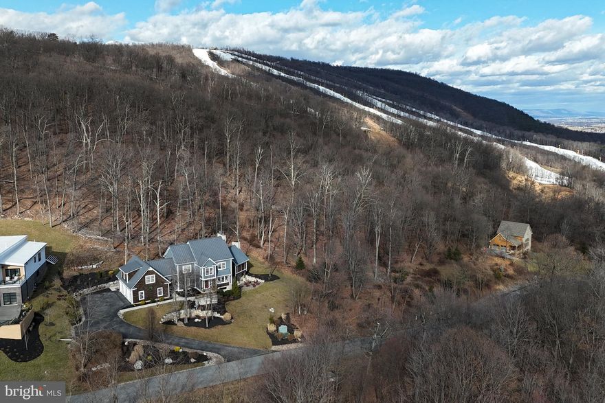 Custom Post & Beam Mountain Chalet in Whitetail Resort Community. Stunning 5BR/4.5BA custom-built post and beam home in the heart of Whitetail Resort, part of the Vail Resorts family. This rustic yet refined chalet offers reclaimed wood floors, cathedral tongue-and-groove ceilings, and multiple fireplaces. The gourmet kitchen features custom cabinetry, a large island with reclaimed wood countertop, and flows into an open concept living area with oak beams and stone fireplace. Main level includes a cozy den, mudroom, oversized 3-car garage, and dual entries. Upper level boasts a luxurious primary suite with gas fireplace, spa-style bath, and double walk-in closets. Additional bedrooms include a Jack-and-Jill suite and a spacious lounge/game room. Walk-out lower level offers a large rec room with wood-burning fireplace, home gym, full bath, laundry, and potential 6th bedroom. Exterior features include standing seam metal roof, fiber cement and cedar shake siding, stone accents, flagstone patio, fire pit, and fenced yard. Community amenities: pool, hot tub, tennis courts, and year-round recreation. Just 90 mins from DC/Baltimore via I-70. Ideal for full-time living or a luxury mountain getaway.