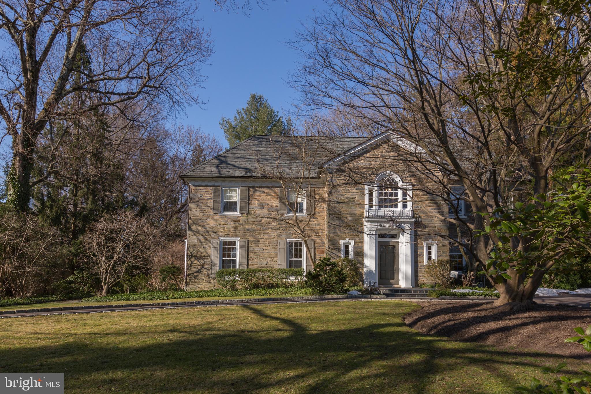 This is a rare chance to own a beautiful home that also is a significant part of Main Line history. Built in the 1930s by the renowned architectural firm Wallace & Warner, this gracious property reflects that periods distinctive desire to develop beautiful residences along the Main Line Pennsylvania Railroad. Aware of its historical significance, the owners have painstakingly maintained and improved this home. They have paid homage to the architects original design with several thoughtful improvements, such as renovating each bathroom and installing a new roof, HVAC system, and top-quality heating and plumbing. This built-to-last home is clearly a quintessential classic—a timeless, graceful, elegant and sui generis beauty. A circular driveway leads to the home, which has a stone exterior. Its beautiful front with Palladian window opens to an expansive and grand reception hall. Step down into the formal living room, which boasts a gracious fireplace, wall molding, and beautiful double windows overlooking the front of the property. The living room opens to a distinctive study, with cozy paneled wood walls and access to a lovely sunroom addition with a slate floor. Off the center hall, the elegant dining room has beautiful touches, including plentiful deep-silled windows, millwork, gleaming hardwood floors, and the adjoining butlers pantry is original. The kitchen has granite countertops, an island, and appliances that include a wall oven/microwave, Subzero refrigerator, gas oven range, and trash compactor. Adjacent to the kitchen is a spacious eating area as well as a desk area. The family room, located in the rear of the home between the kitchen and sunroom, has a triple window and French door to the outside exit and garage. A powder room with vanity sink completes the first floor. An angled center staircase leads to the second floor, with its expansive roster of flexible space, totaling five bedrooms and four full bathrooms. The main suite consists of three rooms: the bedroom has deep-silled windows, a fireplace, built-ins, and a French door to the outside terrace. In addition to the adjoining dressing room, there is an office that contains the beautiful Palladian window overlooking the property. An elegant en-suite, white-tiled bath features a jetted tub, separate stall shower, and pedestal sink. Two additional bedrooms each have en-suite baths. There are two more bedrooms on the second level that share a new bath with stall shower. A separate laundry room with built-ins and closets completes the second level. The homes quality continues seamlessly to the third level, with its pine flooring and substantial millwork. A large bedroom, currently used as a home gym, has a triple window and features a sauna. The second bedroom boasts original built-in drawers and cabinets, as well as four windows and ample storage closets. With yet another bedroom at the top of the stairs, as well as a renovated hall bath with stall shower, this level is perfect for an au-pair or guest suite. The updated lower level has an incredible wood ceiling, exposed stone walls, and a fireplace. Sprawling slate floors give rise to an interesting wine cellar, wine-tasting room, and expansive recreational room. A magnificent handcrafted wood door and hand-carved wood fixtures are evident throughout the wine cellar, where the tasting room and recreation room create an ambiance for timeless entertainment. The beautiful backyard is spacious. In addition to the flagstone patio, perfect for entertaining, there is also a distinctive stone well. A three-car garage provides ample space for vehicles and storage. With its parklike setting and beautiful Main Line streets, you might forget how ideal the homes location is: walk through Bryn Mawr Colleges campus to town, enjoying all that it offers, including the Bryn Mawr Film Institute, several small and independent shops, Ludington Library, the Regional Rail, and so much more.