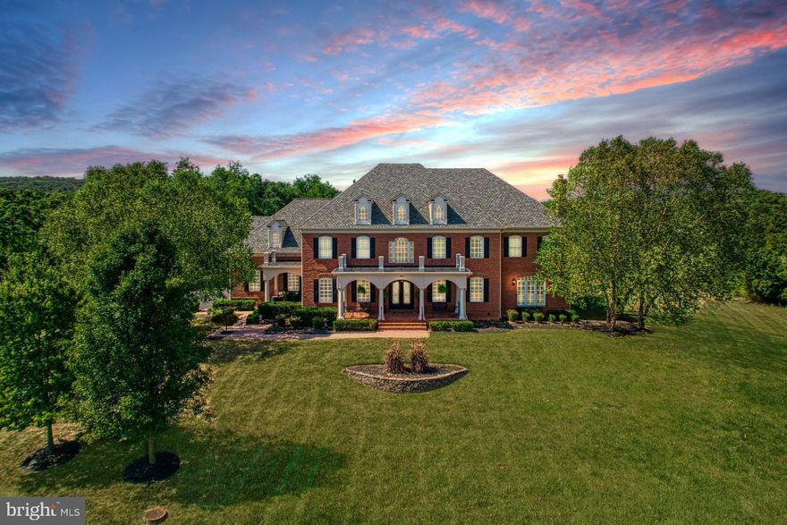 Hidden along a private drive within distinguished Raspberry Falls Golf & Hunt Club, this gorgeous Georgian estate stuns as architecture echoing the region’s historic personality wraps a home of modern luxury. Just over ten acres of natural splendor add atmosphere to garden parties, al fresco meals, and mornings overlooking Catoctin Mountain views. Inside, this award-winning Marquis Grayhaven model has been designed with nearly 12,000 square feet of sophisticated charm and high-end finishings. Discover hardwoods, double-storied ceiling heights, exquisite trimmings, thoughtful built-ins, display nooks, and designer fixtures dotting vistas for rest, work, and entertaining. Boasting every available upgrade, your open floor plan includes a handsome executive office, sunroom for welcoming neighbors, fourth floor au pair/in-law suite, and an incredible lower-level escape for parties and weekend play. Here, your urban retreat serves guests at the sports bar, keeps favorite wines in the cellar, entertains in the theater, and supports recovery within the commercial-grade gym and spa complete with sauna, steam room, and hot tub. In the home’s heart, dual islands, butler’s pantry, endless- cabinetry, and professional-grade appliances assist the chef while the stone-wrapped hearth warms holiday-conversation. As endless windows inspire outdoor living, find yourself lingering on multiple patios, or gathering on the home’s centerpiece stone-clad terrace where you’ll enjoy sun-soaked BBQ’s, sip wines and star gaze around the firepit. Five bedrooms and five spa-like baths care for unwinding. In the primary suite, your sitting room with fireplace, creates cozy evenings in, while a bespoke dressing closet and lavish bath preps nights on-the-town. While on tour, visit the three-car garage with driveway fit for large guest lists, and imagine strolls, with a four-legged friend, by peeks of the golf course and surrounding seasonal beauty.

This beautifully appointed estate home is in the prestigious golf course community of Raspberry Falls Golf & Hunt Club, which is in the heart of Loudoun County Wine and Hunt Country, just north of Leesburg, Virginia. Designed by Gary Player, this spectacular 18-hole course was inspired by the great seaside courses in the British Isles. While golfing, you will encounter rambling streams, bunkers, stone walls, and spectacular rolling terrain, with vistas of the Catoctin Mountains in the background. Additional community amenities include a pool and tennis courts. Raspberry Falls offers a unique blend of private country living and easy access to diverse employment and shopping opportunities in Loudoun and Fairfax Counties. Raspberry Falls is just 30 minutes from Dulles International Airport and an easy commute into Fairfax County, Maryland, and Washington D.C.