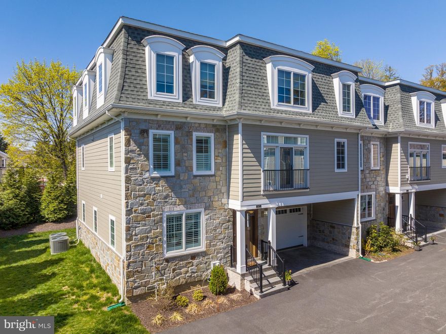 This stunning home shows like a designer model because it was! With 3+ bedrooms, 4 full and 2 half baths, this beautiful Bloomingdale Court end-unit is located in a premium walk-to everything location in Wayne. Upon entering, you are immediately struck by the high-end upgrades and luxurious finishes, including elegant architectural details, designer lighting, abundant natural light, and quality construction. The welcoming family room features a gas fireplace with an eye-catching floor-to-ceiling detail and cozy benches. On this floor you will also find a laundry room with Samsung appliances and built-in cubbies, a powder room, access to the 2-car garage, and doors to the rear yard. On the second level is a gorgeous, sunlit kitchen, featuring Wolf appliances, marble counters and backsplashes, custom range hood, large center island, and wet bar with built-ins and beverage fridge. The adjacent breakfast area offers banquette seating and doors to the spacious rear deck – a peaceful setting that will become a favorite place to entertain or relax after a long day. The great room offers a stunning fireplace with designer tile, built-in shelving and cabinets, coffered ceiling, and French doors to the deck. The impressive formal dining room is perfect for intimate gatherings or grand entertaining. A handsome office with wood paneling is also found on this floor. The upstairs features an expansive primary suite with large closets and a convenient second laundry closet. The private, sumptuous bath includes a large soaking tub, double vanity, and walk-in shower with gorgeous custom tiled wall. Two sunny guest bedrooms with en-suite baths complete this floor. The finished daylight basement offers additional living space for guests or family, with a large bedroom area and full bath. For the ultimate in convenience, there is an elevator that services all floors, from the basement to the upper bedrooms. This gorgeous home is just steps from all the shopping, dining, and entertainment that Wayne has to offer, and less than a .5 mile walk to the Wayne train station for an easy commute into Philadelphia.