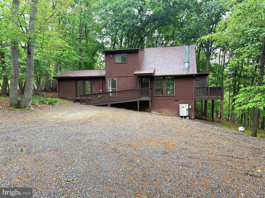 Tucked among nearly two wooded acres in a sought-after golf resort community, this contemporary style cabin offers the perfect blend of comfort, style, and resort living. With 3 bedrooms, 2 full bathrooms, and 1,456 square feet of finished living space, this home is designed to feel both spacious and welcoming.
Inside, gorgeous LVP and hardwood flooring flow throughout the home, while a dramatic cathedral window fills the living room with natural light. A wood-burning stove adds warmth and ambiance, creating the ideal gathering space year-round. The main level features two generously sized bedrooms, while the upper level offers a private retreat complete with a spacious bedroom, full bath, and walk-in closet. The updated kitchen is beautifully appointed with new cabinetry, granite countertops, and stainless steel appliances, combining modern convenience with timeless appeal. Just off the family room, the screened-in sunroom provides a peaceful space to relax and enjoy the surrounding nature in every season. An adjoining open deck is perfect for grilling, outdoor dining, or simply taking in the wooded setting. Outside, the large gravel driveway and parking area offer ample space for guests and multiple vehicles. Optional resort membership packages provide access to an impressive array of amenities, including an 18-hole golf course, Clubhouse Grille & Pub, indoor and outdoor pools, tennis and pickleball courts, a sports center with basketball and volleyball courts, catch-and-release fishing ponds, and spa and wellness services at Sleepy Creek Spa. Conveniently located just 90 minutes from the D.C./Baltimore metro area and only a short drive to Berkeley Springs, this property offers the ideal escape for full-time living or a relaxing weekend retreat.