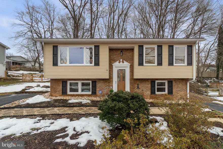 Remodeled and thoughtfully upgraded in 2026, this inviting split-foyer residence offers 3 bedrooms, 2 full bathrooms, and 1,324 beautifully finished square feet in well-established Hilltop Estates. The interior was comprehensively remodeled in 2026, showcasing fresh designer paint, recently installed luxury vinyl plank flooring, plush carpeting, enhanced lighting, replaced windows, and an upgraded HVAC system, creating a cohesive, modern aesthetic from top to bottom. A 2024 roof with a 50-year warranty provides additional long-term peace of mind. Step inside to a bright and welcoming two-story foyer that ascends to the sun-filled living room, where oversized windows invite in abundant natural light and create an airy, uplifting atmosphere. The eat-in kitchen is both stylish and functional, featuring raised-panel cabinetry, striking steel gray granite countertops (2026), and a suite of premium sleek black appliances. An adjacent dining area with sliding glass doors opens seamlessly to the deck, ideal for effortless indoor-outdoor entertaining. Also on the main level, you’ll find a beautifully refreshed full bath and two comfortable bedrooms, including the primary retreat. The lower level offers a warm and versatile walk-out recreation room anchored by a charming gas stove set against a classic brick wall with hearth. Thoughtful details such as chair rail molding and under-stair storage enhance both character and functionality. This level also includes a spacious third bedroom, a second full bath, and a utility/laundry room complete with a workshop area and abundant storage. Outdoors, the expansive, tranquil, and shaded backyard feels like a private escape. Professionally landscaped grounds feature a tiered deck, extensive hardscaping with multiple patio areas, terraced gardens, and a peaceful pond with goldfish and a cascading waterfall feature. Two electrified sheds, a charming porch swing frame, tiered retaining walls in the front yard, and dual paved driveways further elevate convenience and lifestyle appeal.