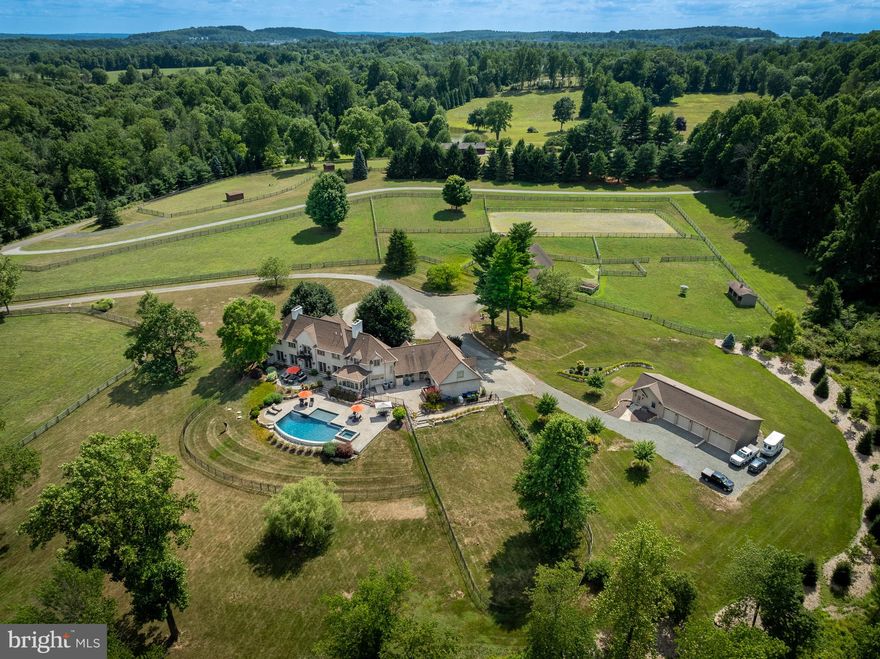 Welcome Home! Enter onto a long tree lined driveway to Seventeen Acre Wood Farm in the heart of Chester Springs. This immaculate property features a 6,337 sqft home, detached 4 car garage, barn with 5 stalls and pastures, inground pool, large backyard and pond with dock! The updated and immaculate Archer and Buchanan 4 Bedroom, 3 full bathroom and 2 half bath home boasts over 6,337 square feet of finished and sun filled space. The exterior is constructed of stucco over concrete block. Enter through the double doors into the foyer with a sweeping custom staircase. The living room boasts two fireplaces and great views of the back living space, pool and property. Continue on into a private study/ library off of the living room. The formal dining room is spacious and also has a great view of the property. Continue into the beautiful kitchen and breakfast area with stainless steel appliances, a fireplace and many improvements from 2021 and 2023 throughout. The first floor also features a butlers pantry, office area, mudroom and second staircase. Upstairs you will find a lovely primary bedroom with a large office, walk-in closets, fireplace and a spacious bathroom with a freestanding tub and separate shower, 2 sinks and radiant floor heating! Additionally there are 3 other bedrooms and 2 full bathrooms as well as 2 sets of washer and dryers on the second floor, and a bonus/rec room. There is a finished basement with a full bar, large living space and a dance studio/home gym. The detached lower garage has 4 bays; 3 bays inside the finished portion and 1 bay designated for lawn and farm supplies. The lower garage also has a climate controlled office space. The main  barn features 5 stalls, tack room with washer and dryer, hay loft and acres of fenced pastures and 90 by 70 riding arena. The outside living space features a large patio and infinity pool and spa built in 2016. The pool area is beautifully placed in the backyard and completely private. The amount of pool parties and gatherings one could host! Continue your time outside with a walk towards the pond to the fireplace and patio. Many summer evenings, you can enjoy your sunsets and smores around this well thought through space. This farm is unquestionably well maintained and well loved. No matter where you turn, you experience beauty and tranquility that Seventeen Acre Wood Farm embodies.