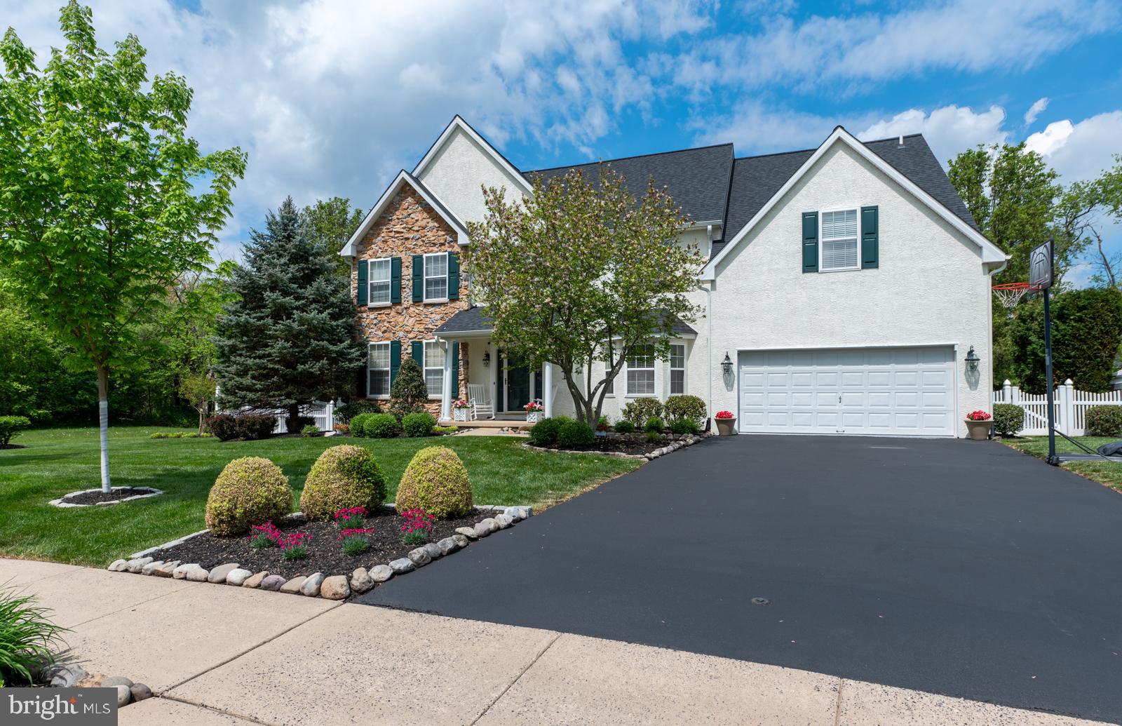 Welcome to this beautifully appointed executive residence nestled on a private, fenced-in lot within the highly sought-after Methacton School District. Boasting 4 spacious bedrooms and 3.5 luxurious baths, this stunning home offers both elegance and comfort, perfect for today’s discerning homeowner. Step into the grand two-story foyer with a striking curved staircase that sets the tone for the sophistication throughout. To the right, a sun-drenched formal living room showcases gleaming hardwood floors, detailed crown and chair moldings, and flows seamlessly into a private study. On the left, an elegant formal dining room offers the same rich hardwood floors and exquisite millwork—ideal for entertaining. At the heart of the home is a soaring two-story family room featuring a dramatic floor-to-ceiling stone fireplace, scenic windows, custom wainscoting, and hardwood floors. The open layout continues into the gourmet, eat-in kitchen with upgraded cabinetry, granite countertops, a center island, stainless steel appliances including a Bosch dishwasher and double oven, plus a pantry. Sliders from the kitchen lead to a beautifully designed patio—perfect for entertaining in the professionally landscaped, fenced backyard oasis. The main level also includes a stylish tiled mudroom, laundry room, and powder room, along with a fully finished two-car garage complete with epoxy flooring and finished walls. Upstairs, retreat through double doors into the luxurious primary suite featuring cathedral ceilings, recessed lighting, and a ceiling fan. A spacious dressing area leads to a remodeled spa-like en-suite bath with a soaking tub, oversized glass shower with bench seating, and double vanities. The suite also includes an expansive walk-in closet, an additional third closet, and a versatile bonus room—perfect for a sitting area, private office, or second walk-in closet. Three additional generously sized bedrooms and a beautifully renovated hall bath complete the upper level. The finished walkout basement offers even more living space, ideal for entertaining, with a home theater setup and surround sound system. French doors lead to a separate room that can serve as a guest bedroom or private office, and a full bath with walk-in shower adds convenience and flexibility. This remarkable home combines luxurious features with a convenient location close to major routes, shopping, dining, and more. Don't miss the opportunity to own this truly exceptional property!