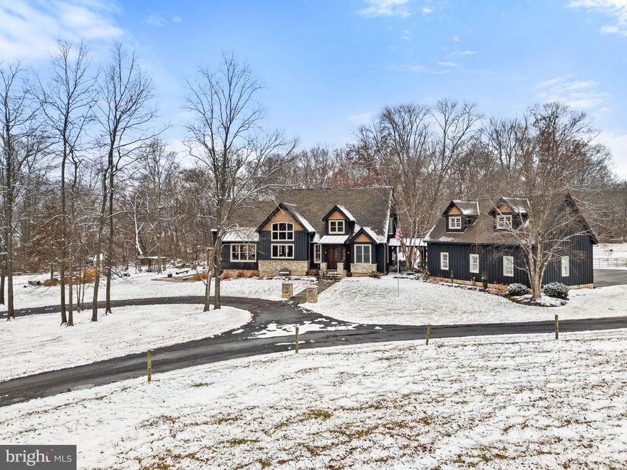 Set on just over 17 pastoral and wooded acres, this architecturally striking post-and-beam estate—crafted in 2006 using renowned Timber Peg construction—brings together exceptional craftsmanship, modern comfort, and the privacy of true rural living. Cedar siding, soaring cathedral ceilings, exposed beams, and Anderson triple-pane windows create a warm, dramatic living environment that honors its natural surroundings.
Inside, over 4,300 finished square feet highlight rustic cherry hardwood floors, custom glass doors, and an awe-inspiring great room with a breathtaking wall of windows, a stunning antler chandelier, and a propane fireplace. Overlooking it all is a 15×20 loft that adds architectural interest and flexible living space.
The gourmet kitchen is designed for both entertaining and everyday enjoyment, featuring granite countertops, stainless steel appliances, a breakfast bar, a built-in breakfast nook, and custom cabinetry throughout. The adjacent butler’s pantry—complete with a custom glass door, granite counters, built-ins, and a wine fridge—adds even more function and elegance. A separate first-floor laundry room also features a custom glass door, cabinetry, and granite surfaces. A mudroom offers convenient everyday entry space.
The main-level primary suite enjoys pastoral views and includes a walk-in closet, raw-edge wood double vanity, soaking tub, and walk-in shower. Each upper-level bedroom features its own private en-suite bath and built-in window seats; two even include charming 7×10 carpeted lofts with ladder access.
This home is engineered for efficiency and comfort with two 60+ gallon hot water heaters, owned solar array, geothermal heating and cooling, and radiant heating in portions of the home and garage.
The expansive 2,650 sq. ft. unfinished, steel-framed walkout basement includes a half bath plumbed for a full bath and rough-ins for a wet bar—ready to be finished exactly as you envision.
Outdoor living shines with a Trex deck and wood-burning fireplace, a hot tub, a stone patio with pergola, and a spectacular 50×20 in-ground saltwater pool (50,000 gallons) with two ionizers. The land is a beautiful mix of open pasture and woods, fully fenced with both wood and electric wire, and includes run-in sheds for livestock.
A full barn—complete with stalls, water, electric, its own electrical panel, and RV hookup—makes the property fully equestrian-ready or homestead-ready. A three-car detached garage with upper-level storage provides additional space for vehicles, equipment, or hobbies.
While wonderfully private, the property remains within a reasonable distance of shopping and conveniences—and a popular local brewery sits just down the road.
This is a rare opportunity to own a distinctive, sustainably built Loudoun County estate where fine craftsmanship, natural beauty, and modern efficiency come together across just over 17 acres of extraordinary living.