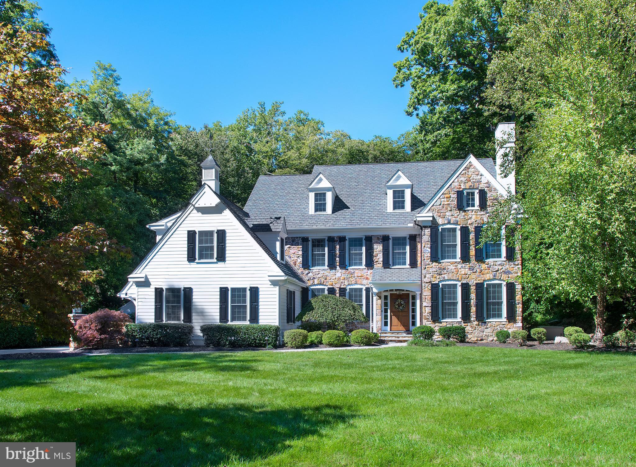 Located in a quiet area between Cornell Drive and Robinhood Road in the heart of Bryn Mawr, this impressive elegant home meets all the family comforts. It is an impeccably-designed, custom 5 bedroom, 4.3 bath estate manor home conceived by Michael Visich architects. Every inch of the special gem reflects quality craftsmanship and attention to detail, from its striking maintenance-free exterior to its generous, finely-finished interiors. Enjoy a beautiful setting in a private, quiet neighborhood, on peaceful lush grounds enveloped by mature trees. The large backyard is very serene, with a view of the stream and hills where the kids can play and explore. Among the high-end upgrades is an expanded driveway, a whole-house generator, steam humidifier, alarm system, top-grade mechanicals, lovely custom millwork, plus a gas fire-pit and 8-person built-in stone hot tub for the ultimate outdoor relaxation! The classic center hall layout presents a light-bathed living room enriched by oak wood floors and a wood-burning fireplace. The seamless flow for entertaining continues across the foyer in the formal dining room with tasteful wainscoting, perfect for family dinners and holidays. A well-equipped butlers pantry with a wet bar and wine cellar enables easy serving and connects to the stunning gourmet kitchen, tailored to the chef. This heart of the home is appointed with Goebel cabinetry, soapstone countertops & island, and premium stainless steel appliances including a Sub-Zero fridge. Have coffee and a snack in the sunny vaulted breakfast room overlooking the picturesque grounds, or step out glass doors to enjoy alfresco dining, BBQs, relaxing in the hot tub, or gathering around the fire-pit on the rear covered flagstone patio. Also by the kitchen is an inviting family room with a wall of windows and gas fireplace. Rounding out the main level are 2 powder rooms, and a convenient mudroom accessing the 3-car attached garage. Retreat to the sleeping quarters where everyone has their own private place to land. The spacious primary bedroom suite calls you to unwind, featuring a tray ceiling, his & her walk-in closets, and a luxurious spa-like bath with sunken tub for freshening up. Four additional bedrooms (2 with en-suite baths), a full hall bath, laundry room, and sitting/computer area are also found on level 2. Lots of fun can be had on the finished day-lit lower level presenting a big carpeted recreation/family/media room, exercise room, separate office, powder room and lots of storage. Adding to the appeal is whole-house audio, 4-zone HVAC, and a water pressure backup sump pump. Even better is the location, close to restaurants, shopping, the train, top schools, and Center City.