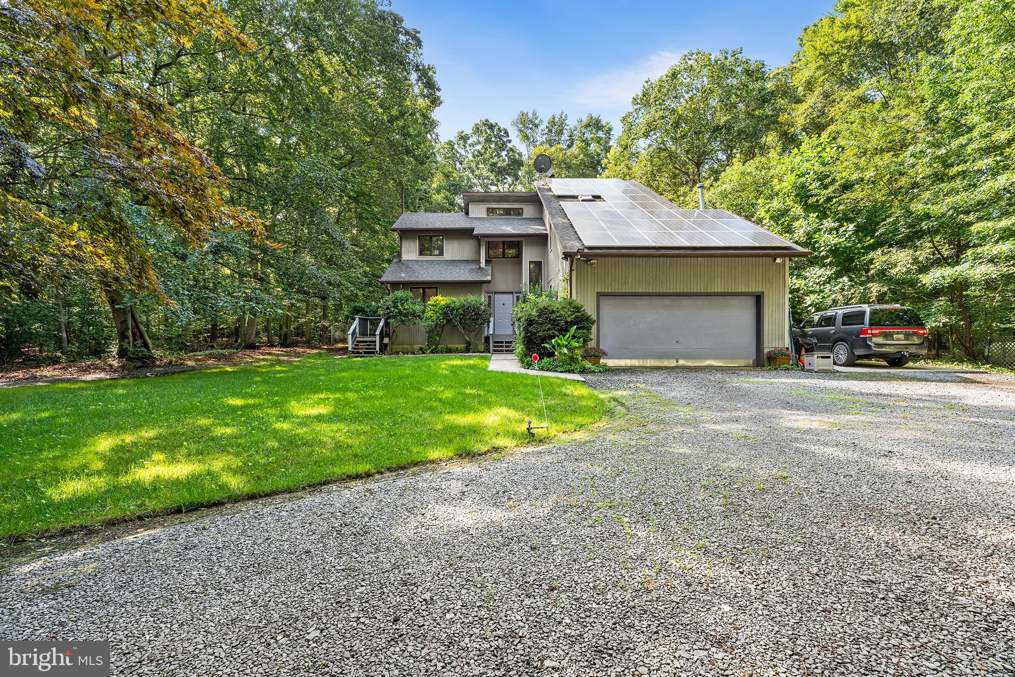Mortgage savings may be available for buyers of this listing. Tucked away at the end of a long private driveway, this beautifully maintained 4-bedroom, 3.5-bath contemporary-style home offers rare privacy on over two acres in the sought-after Chapel District of Talbot County, just minutes from Easton and Route 50 for easy commuting. Surrounded by mature trees and landscaped grounds, this custom-built residence blends natural beauty, comfort, and thoughtful design in a truly tranquil setting. Inside, vaulted ceilings and an abundance of windows create a bright and airy atmosphere throughout the home. The spacious eat-in kitchen offers generous counter space, ample cabinetry, and a pantry, and opens to a dining area with direct access to a full-length deck—perfect for everyday living and entertaining. The deck runs the length of the backyard and overlooks a large in-ground pool surrounded by attractive hardscaping, offering a seamless indoor-outdoor lifestyle. There is also 1/2 bath just off of the kitchen area for convenience. The great room features soaring cathedral ceilings, a sunken floor, and a cozy fireplace, along with sliding glass doors that bring in natural light and connect the interior to the outdoor living spaces. The main level includes to additional bedrooms offering flexible options for guests, family, or as a private au pair or in-law suite with its own separate entrance, full bath, and kitchenette—ideal for multi-generational living or extended stays. Upstairs, the expansive primary suite serves as a peaceful retreat, complete with vaulted ceilings, a private balcony with views of the secluded backyard, and a beautifully updated en suite bath featuring a large jetted tub, custom tiled shower, and a deep walk-in closet with a conveniently located laundry area. The upper level secondary bedrooms also has a private full bath.The backyard is designed for both entertaining and relaxation, featuring a 16x40 deck, a spacious paver patio, and a sparkling in-ground pool, all bordered by mature trees that ensure privacy and serenity. Recent updates include a newer roof, updated HVAC system, and newer pool liner. Additional highlights include an attached two-car garage, a storage shed, and ample parking. This home also features privately owned solar panels, maximizing energy efficiency and offering long-term savings. Combining peaceful wooded surroundings with close proximity to Easton, Route 50, and the amenities of Talbot County, this exceptional property is a rare opportunity for private, energy-conscious living in a prime location.