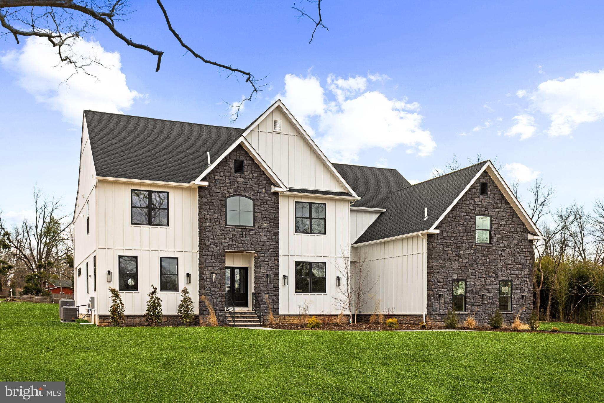 **LAST AVAILABLE** Extensively reimagined, TENNIS POINTE continues to stand as an unrivaled testament to exceptional design, now elevated further in its new and improved Phase II iteration. Seamlessly blending the timeless elegance of Modern Colonial architecture with the rustic charm of Farmhouse aesthetics, each Phase II home offers an even more expansive floor plan than before, with every room thoughtfully enlarged for enhanced comfort & luxury. Undeniably striking, these extraordinary residences are perched atop a raised elevation, their pristine white façades accented with bold stone details. A limestone porch, accessed via a pedestrian path, welcomes you to the entrance, where you are greeted by a towering foyer. Long Leaf Acacia hardwood floors frame a stunning central staircase, setting the tone for the home's grandeur. To the left, the living room captivates with an abundance of windows inviting natural light, intricate trim work, & a breathtaking gas fireplace encased in floor-to-ceiling stone. Across the foyer is the massive formal dining room. Next, you will find a pantry with an added butler prep area. The kitchen, one of three defining focal points of this Phase II residence, is a masterpiece of form and function. Anchored by an oversized island with a waterfall edge, it features Italian Aster Cucine custom cabinetry with marble countertops, Bertazzoni stainless steel appliances—including a professional-grade 6-burner gas oven/range with hood and a JennAir® panel-ready refrigerator—& elegant pendant lighting. A beautifully tiled mudroom offers access to the side-entry door, expansive 3-car garage, and uniquely appointed private study. Featuring intricate trim work, wall sconces, and a refined ambiance, the study offers a dedicated space. Beyond the breakfast area, the great room unfolds with soaring two-story ceilings and a two-story window array, flooding the space with natural light and creating a harmonious connection to the outdoors. The main level also features a proper first-floor bedroom suite, complete with a walk-in closet and a private bathroom showcasing a frameless glass shower and majestic large-format tile. Ascending the staircase, you arrive at an open loft area that bridges the bedrooms. Two bedrooms share a Jack-and-Jill bathroom, designed with a custom floating vanity & an extra-deep tub/shower. Nearby, the laundry room is equipped with a built-in linen closet, sink, and quartz countertop for added convenience. A princess suite, with a spacious walk-in closet & en-suite bath, also offers a unique addition to Phase II. The princess suite now features access to a mezzanine, providing an elevated retreat within the home. Through French doors lies the primary suite, the second focal point of this enhanced Phase II home. This sanctuary is distinguished by a chandelier suspended from a lofty cathedral ceiling, a shiplap-clad feature wall, & two custom-organized walk-in closets. A massive balcony, exclusive to Phase II, extends from the primary suite, offering breathtaking views of the backyard. The primary bathroom is a true spa-like retreat, adorned with immaculate large-format tile. A private water closet, colossal double vanity with a dedicated makeup table, a freestanding soaking tub, and a walk-in shower with custom glass & multiple showerheads complete this oasis. The entertainment-driven lower level, the third focal point, is designed for leisure and enjoyment. It features a media room, game room, fitness area, & a full bar. An additional sixth bedroom provides accommodation for guests or family, while yet another full bathroom & walkout stairs to the backyard enhance functionality. Other exceptional features include high-efficiency dual-zone HVAC, NEST controls, Andersen windows, Therma-Tru exterior doors, a professionally curated landscape package, & more. TENNIS POINTE, in its new and improved Phase II form, is not merely a home—it is a masterpiece of modern luxury.