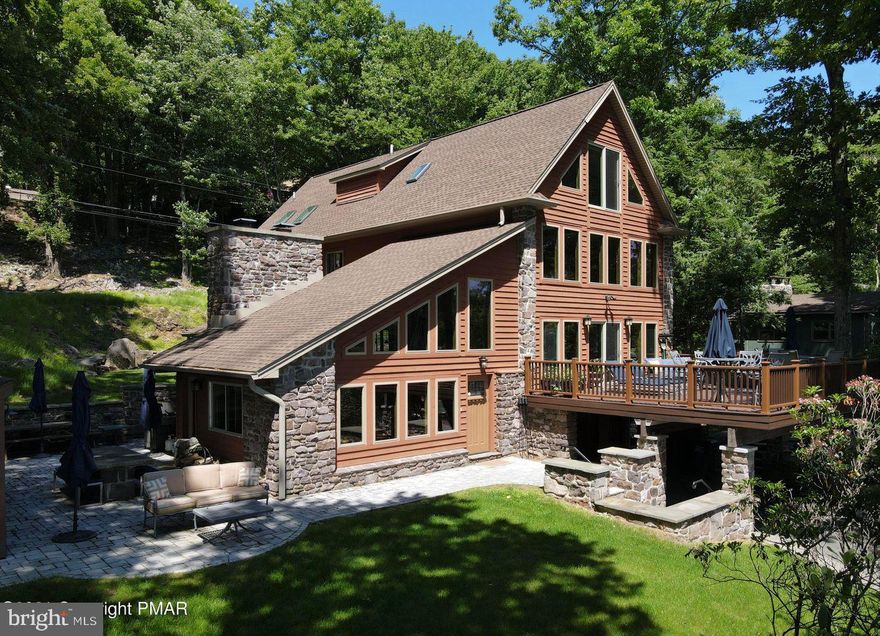 LAKE SHIRE OFFERS ONE OF THE MOST SPECTACULAR VIEWS OF LAKE HARMONY! PRESTIGIOUS CUSTOM CHALET was built w/ superior quality & attention to detail. You will be in awe the moment you enter & see how modern melds w/ old world charm. Living room features the original stone wood burning fireplace & slate floor. Open floor plan make this the perfect home for entertaining. Ultra modern kitchen is a cooks dream w/ granite & stainless appliances & an adjoining kitchenette. Formal dining room leads to a side patio for summer barbecues. Relax by the fireplace in the palatial great room watching your favorite team or reading your favorite book; enjoy lake views while sipping your favorite cocktail in the stocked whisky bar/music room that leads to a grand deck overlooking the lake. Master bedroom w/ his & hers closets & beautiful tiled master bath with tub & shower are on the 3rd level along with 2 more bedrooms & full bath plus a loft.
OH WHAT A VIEW from the 4th level guest quarters. This suite features a spacious sitting area & a dazzling tiled bath. Terrace level has a powder room, storage garage and stocked wine cellar. 100 feet of shoreline with a dock & private beach. This one of kind home is being sold completely furnished (including the wine collection) less a few pieces of artwork. Virtual tour, drone video, floor plans online.