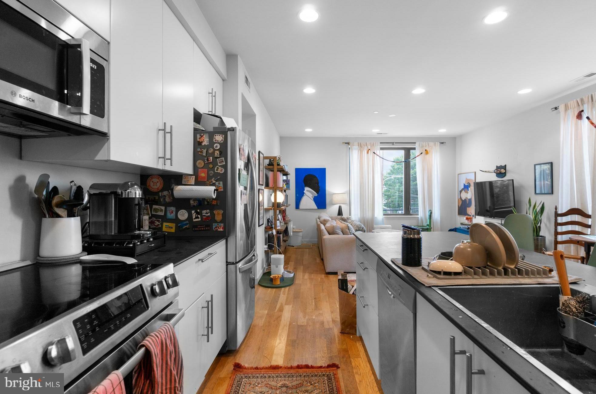 Open House on Saturday, September 13th & 11 AM-12:30 PM! 3D tour available. The main features of this condo with parking included are its ultra-low condo fee of $200/YEAR (because why pay for amenities you may never use) and the fact that this condo is a part of the reNEWBOLD development, which was featured in the Philadelphia magazine and others for its unique features. Built to LEED-platinum standard, the highest tier awarded by the U.S. Green Building Council, the homes feature super‑insulated envelopes and triple‑pane windows, pushing energy performance close to passive‑house levels and aiming to cut utility usage by up to 60%. Construction includes the use of low‑VOC materials, improving indoor air quality for residents. Green roofs recycle water and feed plants, and the green parking surface! This is not your regular development.
Why would you buy it? If you want to live in South Philly for all of its quiet, residential lifestyle and walkability to amazing dining options, but you are looking to live in a condo because you don't want to deal with all the regular home ownership headaches.
Loved by neighbors, Little Susie’s Coffee & Pie is just a 1-minute walk away, and you can get coffee & freshly baked pies. Commercial space on the first floor may be turned into a neighborhood "3rd space" to enjoy coffee and local artist meet-ups. South Philadelphia Tap Room and Second District Brewing are just a few blocks away, while the celebrated dining corridor on East Passyunk Avenue sits about a ten-minute walk away. The Broad Street Line (Tasker-Morris) is a six-minute walk, putting Center City seven quick stops away. Grocery options, pocket parks, and bike routes fill in the daily-life picture, so the car can often stay parked. This is a beautiful location for people to reside in.
When you walk into the unit, you will be treated to the beautiful open-floor concept kitchen with a massive peninsula, dining & living areas. Because it is a corner unit, you have tons of natural light coming in through those big windows facing North & East, and bedrooms face West. The kitchen has Bosch appliances, well-sized cabinets, a dishwasher, and a garbage disposal. Living & dining areas have plenty of space for entertaining your guests & family.
When you walk down the hallway, you will see the first bathroom, the washer & dryer, and two bedrooms, which sit on opposite ends for privacy. Both of them face West, and the first bedroom has a private bathroom. Throughout the unit, you have beautiful hardwood floors. City taxes remain minimal through the 2026 tax-abatement year.
Sustainable construction, ultra-low carrying costs, easy maintenance, parking, rapid appreciation of the development & neighborhood, and a walk-everywhere South Philly address—1800-2 S 16th St #B makes everyday living refreshingly simple.