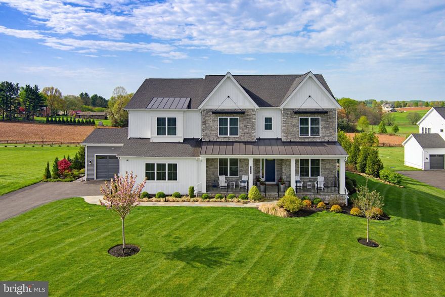 A Rare Offering! Exquisite Craftsmans style estate on 1 acre with sweeping pastoral views. This exceptional four-year-old Toll Brothers built home offers a rare combination of refined design, thoughtful functionality, and elevated indoor-outdoor living—all overlooking breathtaking pastoral scenery. A dramatic two-story great room serves as the heart of the home, highlighted by a floor-to-ceiling stone gas fireplace and expansive windows that frame the serene landscape beyond. The space flows effortlessly into a designer gourmet kitchen featuring quartz countertops, an oversized center island, premium Wolf appliances, and a well-appointed prep kitchen complete with its own refrigerator, sink, dishwasher, and stove. A generous walk-in pantry adds both convenience and storage. The main level is thoughtfully designed to accommodate multigenerational living, offering a private suite with a spacious bedroom, sitting room with wet bar, luxury bath, walk-in closet, and its own dedicated laundry. Elegant details are found throughout, including custom millwork in the formal dining room and private study, along with hardwood flooring spanning throughout most of the home. Upstairs, the primary suite is a sophisticated retreat, showcasing a tray ceiling, private wet bar, and a spa-inspired bath with soaking tub, expansive walk-in shower, and ample closet space. Three additional bedrooms each feature en suite bath, complemented by a conveniently located second-floor laundry room. The fully finished lower level extends the home’s versatility with a sixth bedroom or fitness space and an upgraded wet bar with wine storage, designer tile backsplash, and custom lighting. Outdoor living is truly exceptional. A covered patio, accessed through French sliding doors from the great room, features a second fireplace—perfect for year-round enjoyment. In addition, a separate outdoor kitchen and living area includes a built-in grill, dedicated prep space, and ample room for dining with table and chairs, all perfectly positioned to take in the sweeping pastoral views. Extensive hardscaping, including a paver patio and fire pit, creates an ideal setting for both intimate gatherings and large-scale entertaining. Additional features include a whole-house generator, irrigation system for both front and rear grounds, upgraded lighting throughout, and a six-zone in-ceiling sound system. This is a rare opportunity to own a meticulously upgraded, turnkey residence offering luxury, privacy, and exceptional outdoor living in a truly scenic setting.