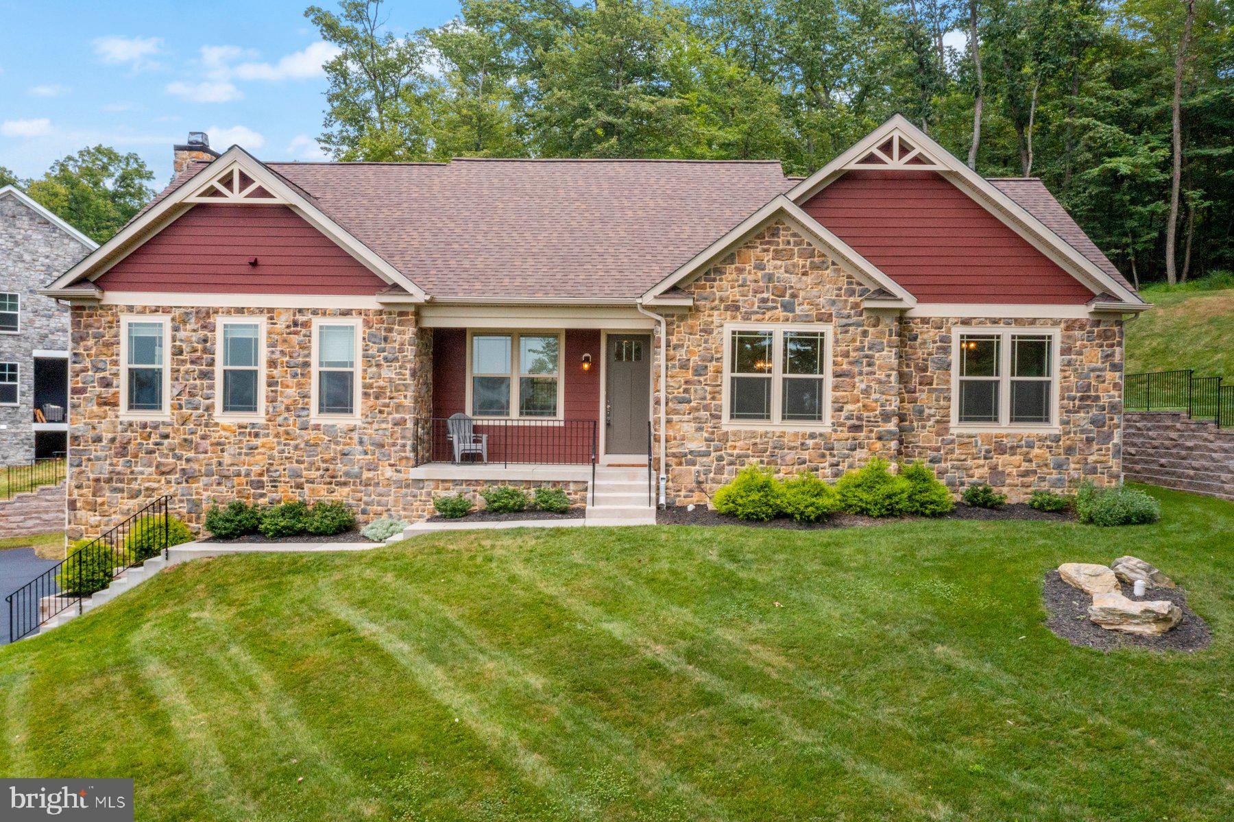 Stunning Aspen Rancher at Lake Linganore – 6606 Accipiter Dr. A rare, move-in-ready ranch home offering spacious single-level living, top-tier luxury finishes, and access to premier Lake Linganore lifestyle— all in a prime New Market location. Built in 2021, this 2,755 sq ft home has 4 spacious bedrooms and 3.5 bathrooms in the sought-after Aspen community. As you approach, you immediately notice the quality of construction and grand scale of this perfectly framed home. This beautiful home boats a striking stone front façade, architectural gables with decorative trim, professionally designed landscaping, and elegant stone retaining walls that enhance its curb appeal. Pull into the expansive driveway that has been newly paved, providing ample parking and a fresh, updated look. Discover an oversized 3-car garage with tandem space, perfect for a golf cart or extra storage. Prominently nestled on 0.39 acres in the Lake Linganore community, enjoy year-round mountain vistas, a beautiful integration into the natural landscape and all the modern amenities you desire. In the rear of the home, an expansive Trex deck overlooks a lush, wooded lot— a peaceful backdrop for outdoor living. Take in breathtaking sunrises and sunsets from your hilltop perch or front porch, with panoramic views of the Catoctin Mountains. As you enter, you are greeted by a beautiful open concept with an expansive gourmet kitchen featuring double wall ovens, cooktop, oversized island, quartz countertops, built in wine fridge and walkthrough pantry, perfect for entertaining and everyday convenience. The living room is the heart of the home with cathedral ceilings, recess lighting, and a stunning floor-to-ceiling stone wood-burning fireplace. Expansive floor-to-ceiling picture windows flood the space with natural light while showcasing breathtaking mountain views. For the ultimate convenience, custom power Solar shades allow you to open and close your window treatments with just the push of a button. Enjoy seamless indoor-outdoor flow with sliding glass doors off the living room that open to a large deck — ideal for relaxing or hosting guests. The front facing dining room welcomes gorgeous mountain views, perfect for everyday family meals or hosted dinners beneath its beautiful chandelier. The main level features beautiful LVT flooring, spacious coat closet, centrally located laundry room and convenient half bath. A spacious primary suite comes complete with a large walk-in closet, designed with custom shelving and a beautiful, wooded view of the rear yard. The primary has a lovely en-suite bath with dual vanities, a large soaking tub, private toilet room and glass-enclosed walk-in shower. A second bedroom connects to the primary suite—perfect for a nursery or office— front facing and offering stunning mountain views. The third bedroom features its own en-suite bath with a tub/shower combo and is privately situated on the opposite side of the main floor. Follow the gorgeous oak staircase down to the lower entry level of the home. The lower level offers a private bedroom with en-suite bath, featuring a large walk-in closet and glass enclosed walk-in shower— ideal for guests or multigenerational living. The spacious unfinished side of the lower level provides abundant room for storage or recreation and includes a secure, private safe room – offering peace of mind and unlimited potential to tailor the space to your needs. Full HVAC system and high-end finishes deliver year-round comfort and low maintenance. Additional features include an epoxy garage floor and convenient storage closest located just off the garage on the lower level, offering additional space for seasonal items, tools or gear. Nestled in the Lake Linganore community, residents enjoy access to deep-water boating, sandy beaches, multiple pools, nature/bike trails, pickleball courts, as well as top-rated schools nearby—Deer Crossing Elementary, Oakdale Middle, and Oakdale High.