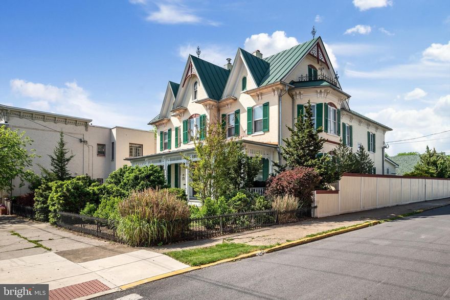 “Green Gables.”  This carpenter gothic style 1864 brick Victorian gem is a world unto itself.  Stunningly well cared for with a “secret garden,” a custom fenced, formal garden with gazebo, garden porch, and patio area.  The welcoming front porch has the signature Victorian gingerbread and is shaded from the street by 9foot boxwoods, making it a wonderful place to relax and watch the world go by.  Enter through the etched glass double front doors.  The stunning center-hall style home features the soaring staircase ahead, with a huge dining room with bay window and original details to the left.  On the right, two living areas (formal and family) can be separated by large functioning pocket doors.  The front room has crown molding, built-in shelving for books, a bay window, and a wood burning fireplace for cozy winter evenings.  The rear living space has crown molding, and more built-in shelving.  The back of this home is also functional and gracious, with an updated kitchen, a butler's pantry with a sink, 2nd fridge, storage closets and cabinets, half bath, and a 4-season porch with its own mini split heating and air system- all walking out to the private fenced garden, patio area and gazebo.  Upstairs, the primary bedroom features lovely woodwork and a modern ensuite bath.  The other 3 bedrooms share a hall bath with clawfoot tub/shower, and another full bath with a soaking tub and separate tiled shower.  The laundry room is located on the bedroom level for added convenience.  The unfinished attic provides extra space for storage or to create additional living area.  A detached 2-car garage with attached workshop provides off-street parking and is accessible through the back garden.  There are so many charming details in this home to explore and discover!   All within walking distance to downtown Martinsburg’s 12+ restaurants and unique shops.