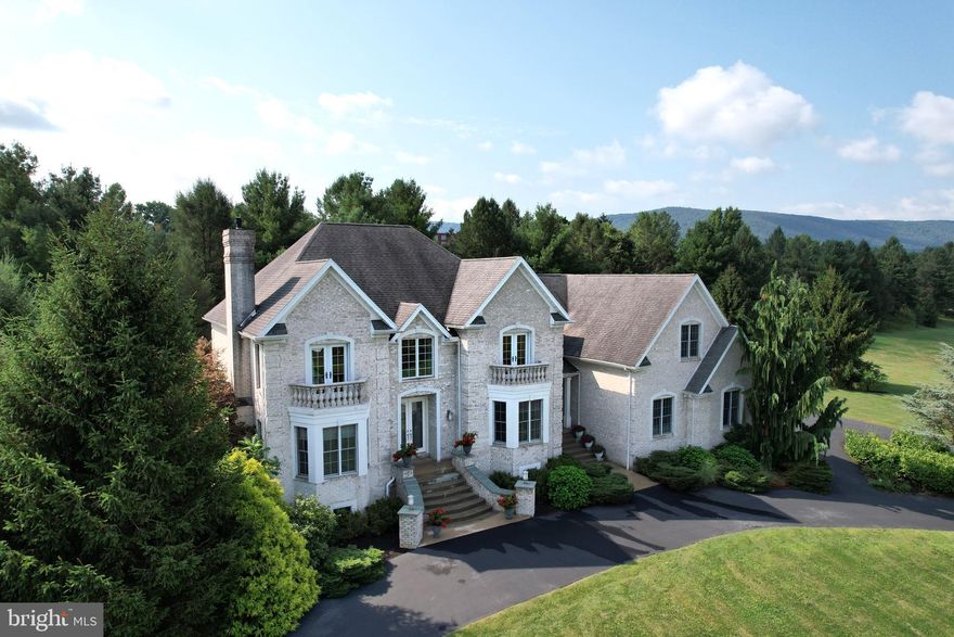 Be prepared to be wowed by this Aspen Heights gem!  This gorgeous, custom-built Premier Homes brick two-story features quality materials and luxury features throughout.  Perched slightly above the road this grand home welcomes you with arched walls on either end of the circular driveway, beautiful bay windows with stone balustrades on Romeo & Juliet balconies above, quoined corners, and a curved entry staircase with lighted accent pillars.  Enter the beveled glass double doors into a spacious 2-story foyer featuring Alhambra Spanish tile, dual closets, and a wood staircase with a custom contemporary railing and notice the expansive rosewood floors, and nine foot & cathedral ceilings beyond.  The lovely front living room is a pleasant place to sit and talk or read with its built-in bay window nook, dentil crown molding, gas fireplace with granite surround, sconce lighting and arched opening.  An architectural delight, the two story great room amazes with its many windows, shadow box accents, granite hearth with gas fireplace and TV, Bose surround sound, and plentiful sconce and recessed lighting.  A chef's dream, the spacious kitchen boasts abundant high-quality embellished maple cabinets, granite countertops, tile backsplash and under cabinet lighting, stainless steel appliances including a Thermador double oven and five burner cooktop, a Bosch dishwasher, triple corner window and sink area, a desk area, a large island with sitting area, a prep sink, & pendant lighting, and a sizable nook area with built-in shelving and access to the rear patio.  Built for entertaining, the expansive dining room with its bay window, crown molding, surround sound, and arched opening is perfect for hosting large gatherings.  Strategically placed in the back corner, the tucked away study with its beautiful built-in desk, shelving, window seat, and full bath with custom tile floor, tub/shower combo with jets, and granite top can double as a main-floor guest room.  Retreat upstairs through double doors to the enchanting primary suite featuring oak flooring, a tray ceiling with crown molding, built-ins, French doors to an exterior balcony, a walk-in closet, and a luxury bath boasting a dual maple vanity with granite tops, tile flooring, jetted tub, toilet closet, and a jetted shower.  Past the reading loft you'll find the back bedroom with triple corner windows, a walk-in closet and access to the hall bathroom that features Spanish tile, dual sink maple vanity with granite top, a tub/shower combo with body jet, and a skylight.  The front bedroom pleases with its oak flooring, French doors to an exterior balcony, vaulted ceiling accent, built-ins, and ensuite bath with custom tile, granite top, and shower with body jets.  Down the hall delight in the spacious fourth bedroom complete with a reading nook, deep closets, storage eves, and plentiful recessed lighting. Second floor laundry with a utility sink and storage cabinets complete the top floor. A blank slate awaiting your finishing touches, the substantial basement boasts pre-plumbing for a future bath, geothermal heating & cooling system with basement HVAC runs, new water heaters and water softener, central vacuum, and additional stairs for easy storage access from the oversized three car garage. Relax or entertain on the back patios taking in the private 1.88 acre yard and enjoy views of the surrounding mountains. Resting minutes from the Village of Boalsburg with its restaurants and shops, Tussey Mountain, Rothrock State Forest, Mountain View Country Club, downtown State College and Penn State's campus, and easy access to Rt 322 and I-99, you'll love this end of town and the esteemed Aspen Heights neighborhood.  Come home to 128 Aspen Drive!