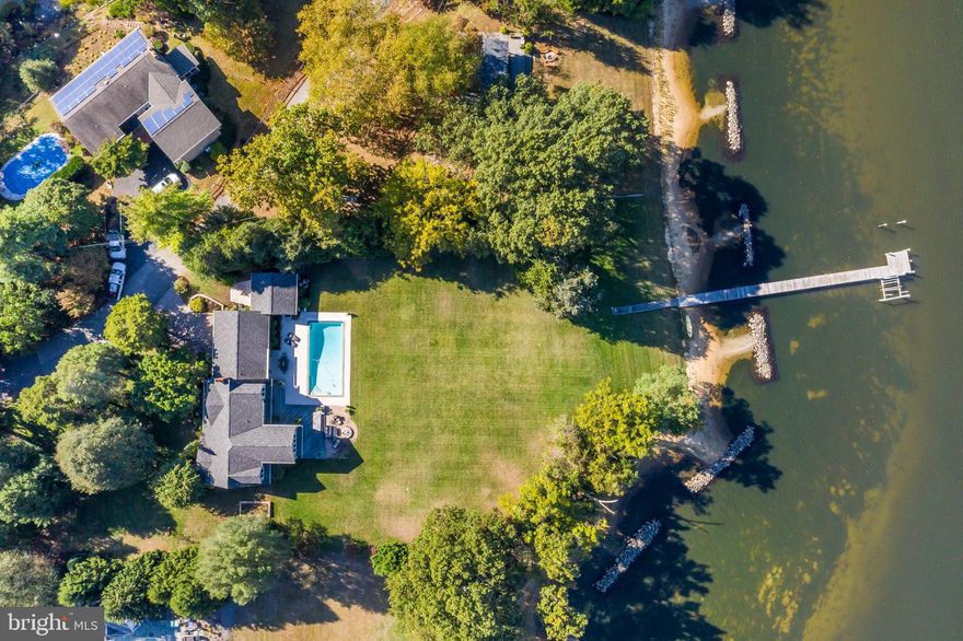 Magnificently sited on level 1.28 Acre lot on Mill Creek with  approximately 200 feet of waterfront, waterside pool, deck, patio, private deep water pier, living shoreline and expansive views of the Magothy River.  Gracious, upgraded home with open floor plan,  wood floors and fireplace is perfect for entertaining. Main level has one Bedroom and private office. Spacious master and 2 additional bedrooms on 2nd level, recreation room on lower level. Bonus: Four garage spaces! Steps from Twin Harbors community and beach. Convenient commuting location to Baltimore, Annapolis and Maryland s Eastern Shore. Mattaport tour, survey and floor plans can be found on Bright documents