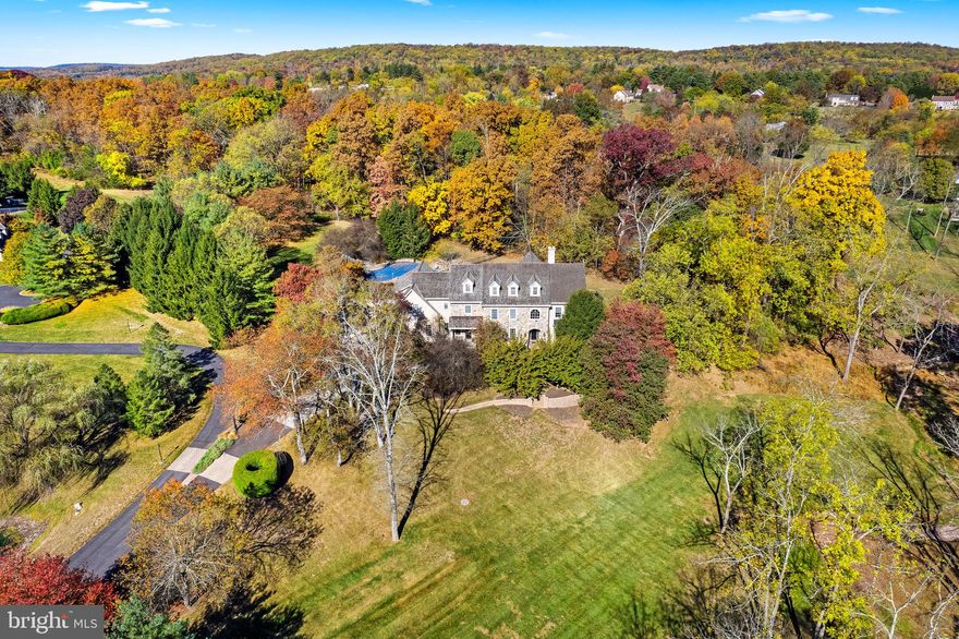 Superior craftsmanship is evident in this gorgeous stone front estate property in coveted Upper Makefield Township. Nestled on 4 private acres behind a mature tree lined drive and offering wonderful meadow and pond views. This elegant and spacious home highlights beautiful architectural elements and gracious finishes including rich hardwood floors, custom millwork, transom windows, French doors, and designer touches around every corner. The stunning, recently updated Gourmet Kitchen is spectacular and features a significant island with seating for 6, chic herringbone brick backsplash, high-end appliances and entertainment access to a well-equipped butler’s pantry featuring a dishwasher, beverage refrigeration and more! The Gathering Room is comfortable and centrally located off the kitchen with access to the outdoor space and fieldstone accented Sunroom that offers tremendous versatility. The upper-level hosts 5 spacious bedrooms, updated secondary baths, convenient laundry room and a walk-up 3rd floor offering wonderful opportunity and an abundance of storage. The finished walk-out lower level has something for everyone including a bar, gym with sauna, custom kid centric play space, theater room and full bath. The exterior of the home offers plenty of space to relax and unwind whether you are on a chaise lounge sunning by the saltwater pool listening to the soothing sound of the waterfall or hosting a gathering on the extensive paver patio. Additional amenities include a 4 car garage, exceptional mudroom with custom built-in cubbies, wonderful ceiling heights throughout, designer light fixtures, chandelier lift, and located within the highly desired Council Rock school district with blue ribbon elementary school, Sol Feinstone. Enjoy the style and luxury of this exceptional property!