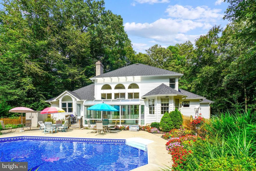 RESORT-STYLE LIVING NEAR METRO AMENITIES!  STATELY COUNTRYSIDE COLONIAL with ENVIABLE POOL OASIS in exclusive Gambrills community of HERMITAGE HILLS!  2.05 Lushly wooded and landscaped acres with beckoning INGROUND POOL & PARTY PATIO SURROUND.  Natural privacy fence of lofty shade tree umbrellas! Brick-front custom Colonial with professional hardscaping & imposing arched entrance portico.  Masterful millwork & architectural detailing showcasing lustrous hardwood floors & walls of windows drenching rooms in light.  MAIN LEVEL PRIMARY BEDROOM SUITE with spa Bath!  Cathedral Living Room with fireplace & soaring Palladian windows framing verdant views.  Formal Dining Room as well as bistro dining area in Kitchen and expanded outdoor mealtime options by the pool!  Stainless & granite island Kitchen spilling into Sunroom and poolside Solarium.  Fabulous finished recreational lower level.  Multi-vehicle driveway & 2-car garage.  TOTAL PRIVACY yet mere minutes to premier Waugh Chapel shopping, dining & cultural venues.  Convenient to RTs 3/450/97/50, though  YOU WILL NEVER WANT TO LEAVE HOME!