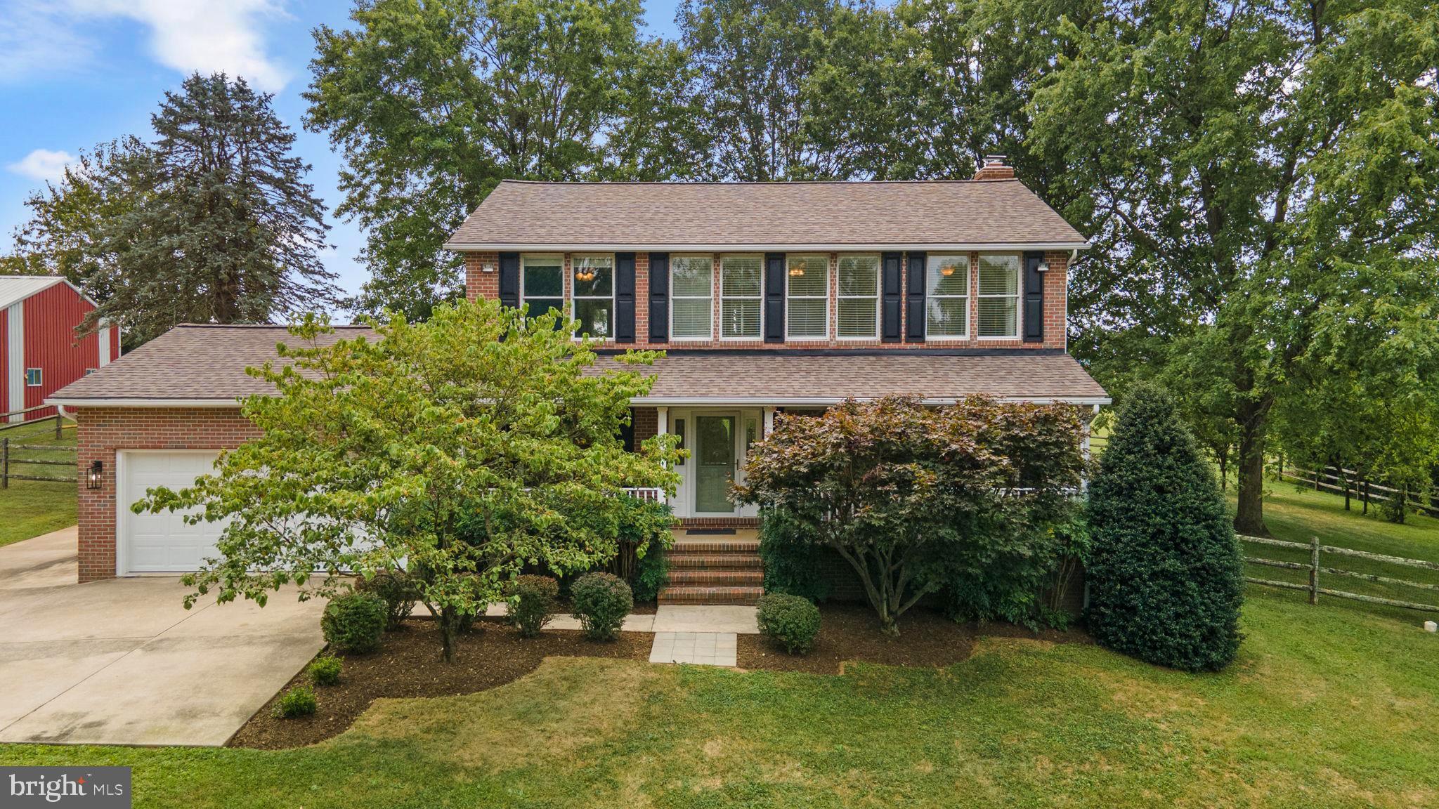 Welcome Home! This grand brick colonial stands proudly on a beautifully landscaped rolling acre, backing to serene farmland. As you enter, you're greeted by beautiful hardwood floors, sundrenched living room and dining room, stairs to the upper level and a hallway through the main living area with a glimpse into the sunroom. The dining room adjoins the kitchen and is adorned with updated lighting, crown molding and chair railing. Step into the custom kitchen with recessed lighting, beautiful ceramic tile floor, white appliance package, plentiful custom cabinetry, quartz countertops, a double sink (with a view), and a unique breakfast bar island, with cooktop and prep sink. Open to the kitchen is a family room with a warm fireplace, and a set of large casement windows, overlooking the deck, yard, and across the adjacent picturesque farmland. A wonderful sunroom adjoins these two rooms with luxury vinyl flooring. On the upper level you'll find the primary suite large ensuite, complete with double sink vanity, jetted tub, shower, and skylight. The main bathroom has a double sink vanity, shower bath and skylight. The hallway laundry closet houses ‘like-new’ stacked front load washer and dryer. The three additional carpeted bedrooms all have ceiling fans, custom window blinds, and spacious closets. The finished basement has a bonus room and a large recreation room. The finished areas are floored with sturdy Berber carpet. The utility/storage room has ample storage space, a utility sink, cabinetry and an exit up through cellar doors to the back yard. The concrete driveway leads to a large parking pad next to the two-car garage. This home boasts premium upgrades. TOUR IT NOW WHILE YOU CAN!