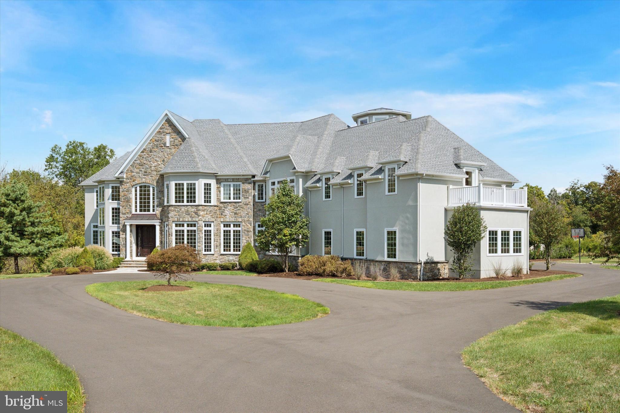 A rare Zaveta-built estate on more than 12 acres in Upper Makefield Township offers the ultimate combination of refined luxury, unmatched amenities, and tranquil privacy in a premier Bucks County location. Purchased only months ago with retirement in mind, the sellers’ plans changed before they could relocate. The home has never been occupied and remains in pristine condition—an exceptional opportunity for the next owner to enjoy this remarkable residence without delay.
Crafted in 2018 by Zaveta Custom Homes, the property reflects timeless architecture, meticulous attention to detail, and superior construction. Across three levels and more than 11,400 finished square feet, the floor plan has been designed for both intimate family living and grand-scale entertaining. Wide-plank maple hardwood floors, soaring 10-foot ceilings, a curved central staircase, and walls of windows highlight open living spaces bathed in natural light.
At the heart of the home, a spectacular gourmet kitchen anchors daily life and entertaining. Featuring dual oversized islands, four ovens, two cooktops, pot filler, deep fryer, ice maker, and two spacious walk-in pantries, it is both functional and inspiring. Adjacent gathering spaces include formal and informal dining areas, an expansive family room, and a butler’s pantry with wine storage and wet/dry bar, ideal for hosting.
The residence is designed with leisure and retreat in mind. A resort-style indoor saltwater pool with slide, heated spa, and full bath allows for year-round enjoyment. The third-floor observatory offers 360-degree views for stargazing and celestial events. On the lower level, 10-foot ceilings accommodate a large craft room with quartz counters, a game room, an 800-bottle wine room, and a secured panic room supported by a full home surveillance system.
Living spaces include 5 bedrooms, 6 full baths, and 2 half baths, each designed with privacy and comfort. The primary suite is a true sanctuary, complete with spa-inspired bath, soaking tub, walk-in closets, a private balcony, and a dressing area/vanity. Secondary bedrooms all feature en-suite baths, providing excellent accommodations for family, guests, or multigenerational living. Multiple studies and flexible spaces allow for work-from-home convenience.
The estate’s grounds are as extraordinary as the home itself. A long, sweeping driveway leads to the oversized three-car garage and additional parking areas. Terraces, balconies, patios, and outdoor retreats expand living to the outdoors. A private quarter-mile trail winds through specimen plantings, including over 6,000 daffodils and narcissus, creating a landscape that feels like a private arboretum. Extensive hardscaping, exterior lighting, and thoughtful design enhance the outdoor experience.
Utility systems and security are equally impressive. A 50KW whole-house generator ensures peace of mind. The home is supported by well water, on-site septic, propane-fueled heating, central air, and advanced exterior camera systems. Every element was designed to provide both comfort and confidence.
While the setting feels worlds away, the property’s location is unmatched. The estate is just four miles from the boutiques and dining of historic Newtown, nine miles from the I-295 corridor for commuting to New York City or Philadelphia, and only a mile from award-winning Sol Feinstone Elementary in the Council Rock School District.
This home is essentially brand new to the market—purchased but never lived in—and is move-in ready for its next chapter. The sellers’ change of plans has created a unique opportunity for a discerning buyer to claim one of Bucks County’s most distinctive properties.