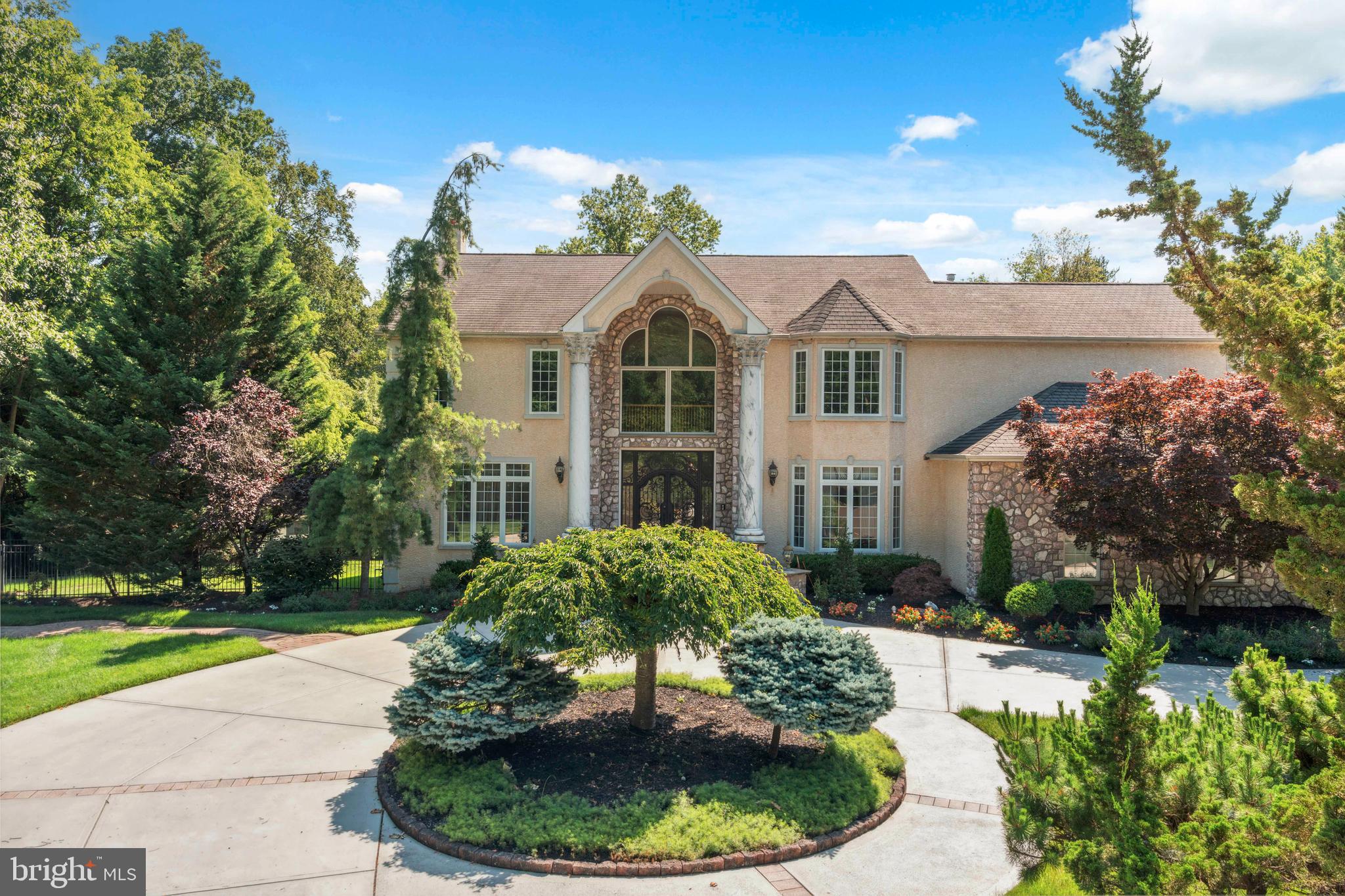 Welcome to this extraordinary residence, perfectly positioned in a private cul-de-sac within the highly sought after Council Rock School District. Offering five bedrooms, five full bathrooms, and a half bath, along with a three car garage, this home is the epitome of luxury, functionality, and timeless design.
From the moment you arrive, the stone facade and wrought iron double doors create an unforgettable first impression. Step inside to a two story foyer, where a sweeping curved staircase sets the tone for the home’s elegance. The foyer is flanked by a formal living room with wainscoting, crown molding, and French doors that lead seamlessly into the family room, as well as a formal dining room with tiled floors and crown molding, ideal for hosting gatherings.
The heart of the home is the expansive chef’s kitchen, boasting rich cabinetry, a six-burner gas stove, a wine refrigerator, a walk-in pantry, and a grand center island perfect for entertaining. A sunlit breakfast area with wet bar opens onto the balcony, while the adjoining family room features hardwood floors, a stunning stone fireplace, and direct access to the outdoors. The private office, with custom cherry built-ins and recessed lighting, provides an inspiring work-from-home environment. A powder room completes this impressive main level.
Upstairs, the primary suite is a luxurious retreat with hardwood floors, crown molding, recessed lighting, and a cozy electric fireplace. French doors open to a partially covered balcony overlooking the serene backyard. This suite also includes a private sitting room, two walk-in closets, and a spa like en suite with intricate tilework, a double vanity, Jacuzzi tub, and oversized stall shower. Three additional bedrooms complete this level, including a princess suite with private bath, another en suite bedroom, and a fourth bedroom with nearby hall bath. A laundry room with cabinetry and utility sink adds convenience.
The walkout lower level is designed for unforgettable entertaining. Here you’ll find a home theater that rivals the cinema, a gym area, a sauna, a versatile sitting area with electric fireplace, a full kitchen, bar, and a full bathroom with stall shower. There’s also an additional bedroom, making this level perfect for guests or extended family. Step outside to a covered paver patio that leads to a resort-like in-ground pool with hot tub, surrounded by professional landscaping, an entertainer’s dream for the warmer months.
The exterior is equally impressive, featuring a horseshoe concrete driveway, lush greenery, and a setting designed for both beauty and privacy. For added peace of mind, the home is equipped with a gas-powered backup generator.
This remarkable property combines elegance, comfort, and functionality in every detail. With its ideal location in Council Rock School District, exquisite interior finishes, and resort style amenities, it offers a rare opportunity to own a true estate home.