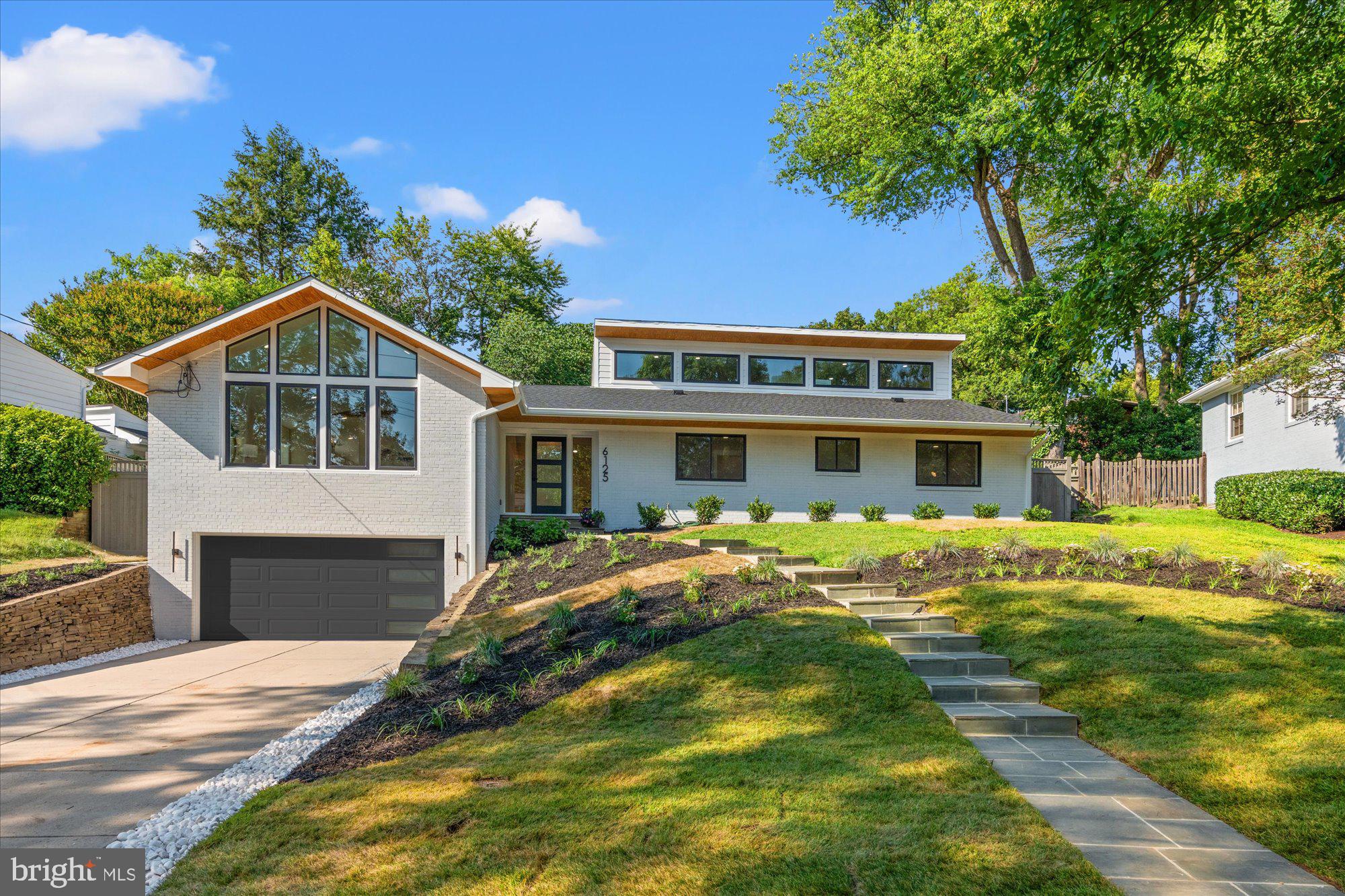 Stunning renovation and expansion of a Mid-Century Modern Retreat in Sought-After Fort Sumner. Welcome to the new home you didn’t know you would be falling in love with. Dogwood Restoration has created the perfect blend of California contemporary with a nod to mid-century design in this unique show piece with over 5,000 square feet of luxuriously finished space. Modern elegance and timeless details abound in this fully renovated and expanded six bedroom, four full and one-half bathroom home, ideally situated on a beautifully landscaped quarter-acre lot in Bethesda’s coveted Fort Sumner neighborhood.
From the moment you arrive, this striking residence impresses with clean architectural lines, soaring ceilings, and an open, light-filled floor plan designed for both everyday living and sophisticated entertaining. Thoughtfully reimagined with premium finishes and high-end systems throughout, no detail has been overlooked.
Experience a warm welcome in to the main level through a custom front door and dramatic entry hall running the full width of the house, with vaulted ceilings, a stunning center chandelier, coat closet and half bathroom with custom wall covering. The expansive living and dining areas with walls of windows, sleek wide-plank hardwood floors and incredible cathedral ceilings are anchored by a beautiful stone fireplace. The designer chef’s kitchen is filled with custom cabinetry, Calcutta gold quartz countertops, top-of-the-line Thermador appliances, including two dishwashers and a generously sized island with prep sink and seating for four, and a separate pantry. A beautiful wine bar with storage and curved ceiling detail and double glass doors to the rear flagstone patio complete the living section of this level.
The bedroom wing of the main level includes a sumptuous primary suite, with expansive walk-in closet and incredible spa-like full bathroom with glass shower, separate soaking tub, dual vanities and heated marble floors. Two additional secondary bedrooms, a stunning full hall bathroom and convenient main level laundry room complete the main floor.
Retreat upstairs to a fabulous upper-level family room and private guest bedroom with a full en-suite bathroom. The expansive lower level includes a generous recreation room, custom mudroom, a wine bar and game room, two huge bedrooms, each with double closets, a stunning full bathroom, extra storage and access to the home’s oversized two car garage.
Enjoy outdoor living on the expansive, fully fenced, pool-sized lot with a flagstone patio, mature landscaping and beautiful stone retaining wall -- perfect for entertaining or relaxing in a peaceful setting. Located just minutes from the Capital Crescent Trail, downtown Bethesda, and top-rated schools, this home offers a rare blend of design, comfort, and location.
Don’t miss this one-of-a-kind modern masterpiece in one of Bethesda’s most desirable neighborhoods. Welcome home!