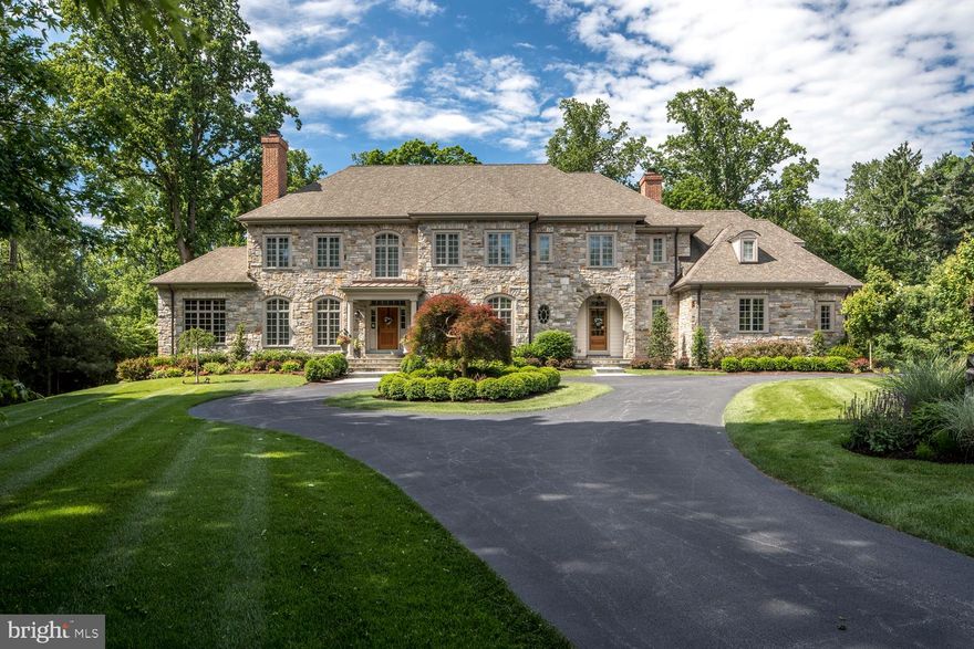 A custom-built masterpiece on a prestigious hidden-gem street in Villanova's coveted estate enclave! Enjoy a one-of-a-kind living experience with top-quality construction & impeccable design by McIntyre/Capron with attention to every detail. Occupying the site of the former carriage house of the J. Kearsley Mitchell, Jr. estate, this gorgeous new gem respects the character of that era & retains some special remnants, like an old carriage house door & reclaimed stone fireplace. The setting on 1.44 acres is a private sanctuary graced by beautiful landscaping, specimen plantings & mature trees. Enjoy a stunning yet versatile family home, perfectly located near all amenities & major routes. At the end of a long drive which becomes circular sits this commanding stone residence with estate fencing surrounding the grounds. Airy ceilings, lux finishes, grand rooms & Architectural Digest-worthy transitional decor are among many refined elements that define the thoughtfully-conceived interior. The front-to-rear Reception Hall leads to the rear flagstone terrace overlooking private grounds. Oak flooring, elaborate crown moldings, recessed paneled wainscoting & arched openings between rooms lend a sophisticated air. Host parties in the living room w/ custom built-ins & a see-through double-sided gas fireplace that connects to the exquisite vaulted office. A fully-equipped wet bar with marble checkerboard flooring & elegant powder room offer convenience for entertaining. Soak up the rays in the sunroom with slate flooring & stone detailing that spills out to the rear terrace. The refined dining room is served by a well-appointed butler's pantry. Open to the spectacular Kountry Kraft chef's kitchen with every bell & whistle, including a Wolf range & Subzero appliances, is vaulted breakfast room accessing the terrace. Also adjacent is an open vaulted family room with a stone fireplace & built-ins. A tiled mudroom off the family entrance has abundant storage, a powder room & 3 car garage entry. The master suite is pure bliss w/ a tray ceilinged bedroom, sitting room & spa-inspired master bath. Four other bedrooms, including a suite & a laundry room occupy the 2nd level. The 3rd floor is great for storage or expanded living space. The day-lit walk-out lower level is enormous, versatile & made for gatherings/recreation, w/ an exercise room, full bath & unfinished area. An added bonus is the backup generator which keeps the house running in the event of a power outage.