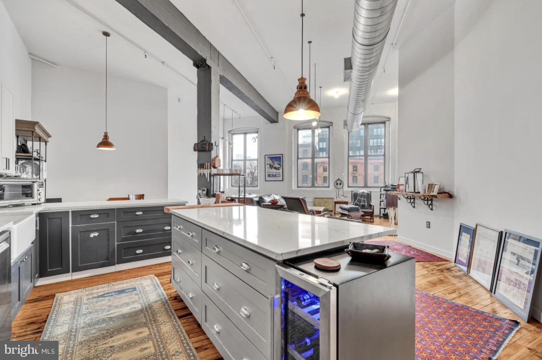 Welcome to this SOHO-style midrise loft in the sought-after Callowhill Industrial Historic District WITH INDOOR PARKING IN THE BUILDING AVAILABLE. This building has a remarkable feature with a second floor door opening directly to the beginning of the coveted Rail Park. Enter a tucked-away unit with an open floor plan. Soaring ceilings, exposed beams and ductwork and original maple flooring with outstanding patina. Newly and professionally painted in Benjamin Moore Decorators White for a perfect fit. Each of a triple set of windows are equipped with tailored 8x4 foot blinds to create a light-filled, expansive living space that invites relaxation and entertainment alike. You will enjoy cooking in the lovely remodeled kitchen with redesigned quartz countertops and a very large island with plenty of space for bar stools, food prep or work space. The kitchen area is complemented by a deep farm sink, blue shaded glass tile, stainless steel appliances including a Bosch dishwasher, Kalamera wine fridge, newly installed silent disposal upgrade, two new matching industrial copper light fixtures and much more.
The generous sleeping area has a huge walk-in closet with built-in shelves and drawers. The bathroom features an incredibly large shower with a stone sitting bench, double sink with newly installed blue tile backsplash and new Toto bidet. Full-size washer and dryer are conveniently located in the bathroom as well. There are industrial stairs that lead to a loft that can serve as a storage area or play space. The great room and bedroom are both equipped with ECHOGEAR full motion HDTV wall mounts with new wiring, power and cable management behind the wall, currently with a keenly placed Bang & Olufsen soundbar in the great room. A stand-out recent improvement is the EcoSmart tankless hot water system located in the bathroom closet and newly upgraded bathroom plumbing. Just dial-in your preferred shower water temperature and never run out of hot water. Digital Nest thermostat system. Added additional GFI's in kitchen and bath.
The newly constructed Philadelphia Ballet Center for Dance is just three blocks away, which along with the Kimmel Center will also host performances. The Broad Street Subway is two blocks away for a quick ride to the Sports Complex. This amazing unit also allows easy, walkable access to Trader Joe’s about five city blocks away, Reading Terminal Market, Cafe Lift, Prohibition Taproom, Juno, Love City Brewing, Wood Street Pizza, Starbucks and so much more that this Philly industrial neighborhood has to offer. At the time of this listing, there are secure indoor parking spots available at the basement level of this building for a monthly fee. Real Estate Taxes paid by the seller are $3910 and Homestead Exemption is approved and active. HOA for this 1,338 square foot unit is $369.66. Keyless entry to the unit, and to the building with a recently installed Alpha Touch entry system. The building’s classical stone exterior renovation was completed in 2025 to preserve the architectural and aesthetic for the new owner.