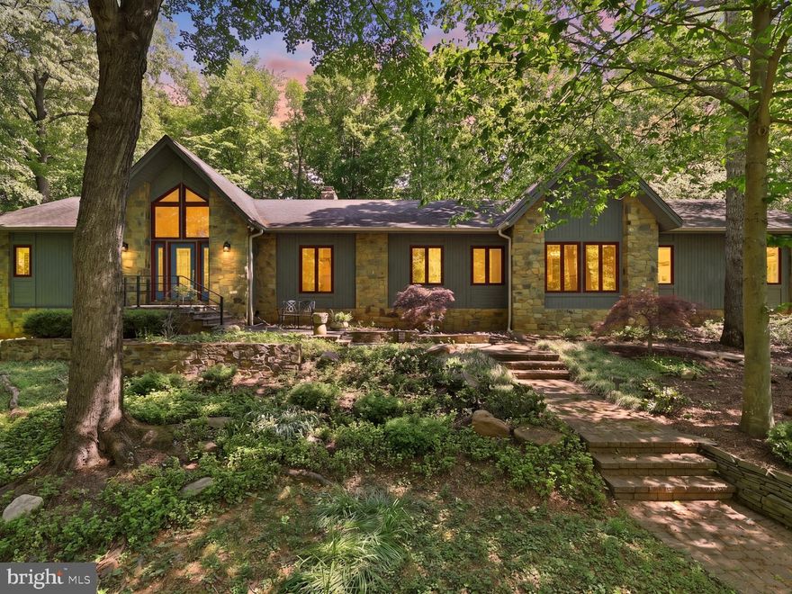 Tucked into a quiet cul de sac off River Bend Road, this stunning cedar and stone contemporary sits on two acres in the heart of Great Falls — one of Northern Virginia's most beloved communities. The location strikes a rare balance: thickly wooded and peaceful, yet an easy commute to D.C. and Tysons. Miles of trails and Potomac River views are just minutes away, at Riverbend Park and Great Falls Park.
Inside, soaring ceilings and gleaming hardwood trim and floors set the tone. Natural light fills every room, and the view from every window is green.
The heart of the home is a highly functional chef's kitchen with granite countertops, spacious island, and sleek black glass appliances. The breakfast area overlooking the garden and pool is a lovely place to start the day. The kitchen flows naturally into an elegant dining room with scenic views of the wooded front yard. A wet bar sits just off the family room for convenient entertaining.
The main floor family room and living room share a two-sided “Crab Orchard Stone” fireplace, and both rooms look out over the yard and in-ground pool. A wall of Pella sliding glass doors opens the family room to an Ipe (Brazilian Oak) deck — a beautiful spot for outdoor dining or unwinding by the pool. A new backyard pavilion with ceiling fan extends the outdoor season, and the bubbling fountain is a birdwatcher’s delight.
The main-level primary suite offers peaceful sanctuary. Its remodeled bathroom — a national first-place award winner — is the kind of space that makes getting ready feel like a luxury. A large custom walk-in closet completes the suite. Also on the main level are two studies with built-in bookshelves and cabinetry, and a beautiful powder room.
The walk-out lower level is highly versatile. Three generous bedrooms and two bathrooms accommodate family and guests. The Railroad Wood-Paneled family room is perfect for play and entertainment. A wine cellar, cedar closet, and bonus room with built-in cabinets and sink round out the space. The oversized storage room can be outfitted to suit the hobbyist or collector. Both the utility room and extra storage room offer generous additional built-in shelving. 
Outdoor features include two lanterns on programmable timers, a Lyman Whitaker wind sculpture, plus. landscape and driveway lighting. A programmable sprinkler system helps keep the grounds looking their best. The oversized garage has been fully renovated with epoxy flooring, custom cabinetry, and Slatwall storage panels. 
Other recent upgrades include a whole-house dehumidifier, downstairs heat pump, pool plastering, gutter screening, plus, designer LED lighting at the front door, garage, and driveway. Closed-cell foam insulation beneath the roof keeps the home energy-efficient and comfortable in every season.
In the Great Falls Elementary, Cooper Middle and Langley High School zones!