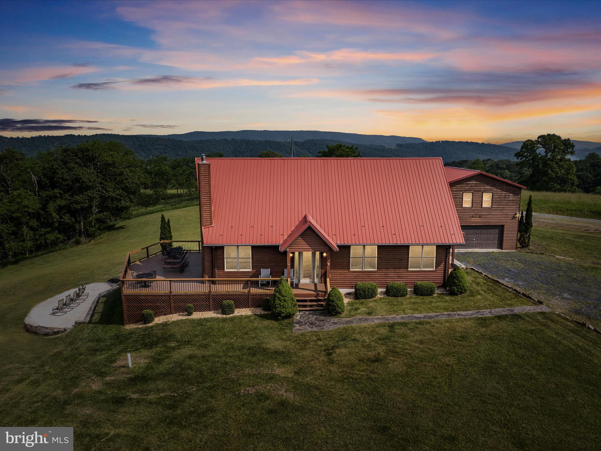 FIRST-TIME OFFERING! Welcome to Mighty Wind Lodge – a one-of-a-kind cedar and glass MOUNTAINTOP chalet with million-dollar panoramic views. Nestled at approximately 2,500 feet elevation in the private, gated Mountain Meadows community, this show-stopping estate sits on two lots (Lot 49 9 acres & Lot 60 21.07 acres) totaling 31.07 acres and offers the perfect opportunity for a luxury family retreat or turn-key vacation rental investment.
Located just 5 miles from scenic Lost River State Park, you’re surrounded by some of the best hiking, horseback riding, and outdoor recreation in the region. The quiet town of Mathias and nearby Lost River are beloved for their welcoming charm, dark skies, and close proximity to the George Washington National Forest. This unique high-elevation location is also a dream for amateur astronomers, with virtually zero light pollution.
The Lodge
Built in 2006, the main home spans nearly 3,000 square feet and features 3 large bedrooms and 2 bathrooms. Designed for year-round comfort and style, the home is clad in natural cedar with a striking red metal roof and is filled with natural light thanks to high-end Pella windows and doors. A dramatic great room with vaulted ceilings centers around a custom wood-burning fireplace featuring a specialized Bell Fire firebox for efficient heating. Flooring includes hardwood and luxury vinyl plank for durability and easy care.
Upstairs, the expansive primary suite offers a vaulted ceiling, ensuite bath, and a private balcony with sweeping views of Lost River ridgelines. The home opens to a large wrap-around deck, ideal for entertaining or quiet moments in nature. The land features mature black walnut trees, hiking trails, and wildlife galore.
Detached Garage & Apartment
A fully insulated and climate-controlled 2-car garage includes a private 1-bedroom, 1-bathroom apartment above, complete with its own entrance, full kitchen, full bath, and HVAC. It’s ideal for guests, extended family, or potential income.
Additional Highlights:
• High-speed fiber optic internet & TV
• Multi-zone HVAC systems
• Stainless steel appliances
• Wrap-around deck with incredible views
• No HOA & no short-term rental restrictions
• Offered fully furnished — ready for immediate use or rental
• Prior short-term rental income: $500+/night (sleeps 12)
• Former wedding venue thanks to unmatched views
Prime Location:
• 2 hours from Washington, D.C.
• 45 min to Wardensville | 20 min to Moorefield | 15 min to Kimsey Run Dam
• 10 min to Lost River State Park
• Nearby: local restaurants, farmers markets, antique stores, and more
Whether you’re seeking a private mountain escape, an income-generating rental, or a unique venue property, Mighty Wind Lodge delivers on all fronts. This is truly a rare offering — don’t miss your chance to own a slice of wild and wonderful West Virginia.