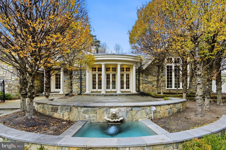 Welcome to Stone Wood, your private sanctuary. An enchanting tree-lined driveway winds through rolling greenery, guiding you to a timeless oasis set on over 5 serene acres. Originally crafted in 1984, masterfully expanded by renowned architect George Stavropoulos in 2000, and exquisitely reimagined in 2021, this estate blends classic grace with modern sophistication. Behind its gated entrance, the drive reveals a stately manor surrounded by manicured lawns, cascading fountains, vibrant gardens, and a tranquil pond beside a resurfaced large tennis court. A full gym and a beautiful guest house complete with its own kitchen further elevate the property’s resort-like appeal. Designed for both intimate living and grand entertaining, the interiors glow with natural light, showcasing intricate millwork, fine finishes, and six elegant fireplaces. The gourmet kitchen—anchored by custom cabinetry, chef-caliber appliances, and its own wood-burning hearth—flows into a cheerful breakfast room and a soaring two-story great room framed by walls of glass. The Versailles-inspired grounds, envisioned by landscape artist Charles Owen, enchant with stone fountains, French wrought-iron gates, and meandering pea gravel paths. Just minutes from Tysons Corner, McLean, Washington D.C. and Dulles Airport, Stone Wood offers refined living in a resort-like setting—an oasis of elegance, artistry, and tranquility.