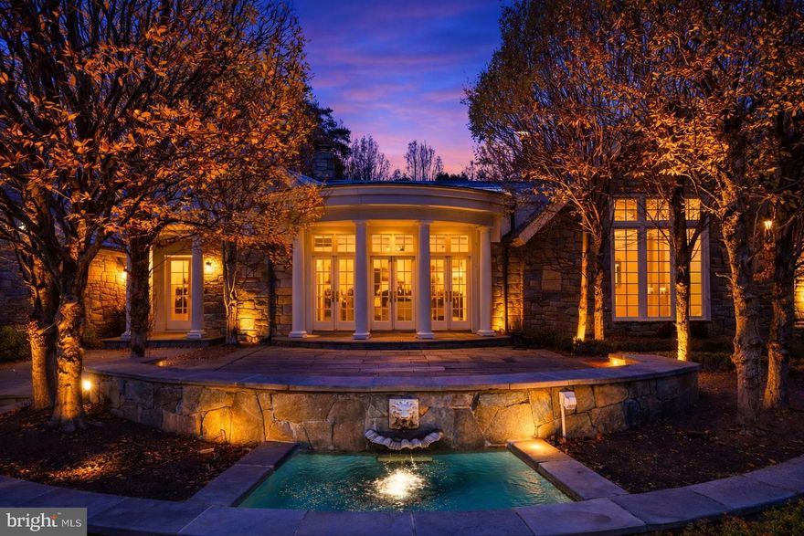 Welcome to Stone Wood, your private sanctuary. An enchanting tree-lined driveway winds through rolling greenery, guiding you to a timeless oasis set on over 5 serene acres. Originally crafted in 1984, masterfully expanded by renowned architect George Stavropoulos in 2000, and exquisitely reimagined in 2021, this estate blends classic grace with modern sophistication. Behind its gated entrance, the drive reveals a stately manor surrounded by manicured lawns, cascading fountains, vibrant gardens, and a tranquil pond beside a resurfaced large tennis court. A full gym and a beautiful guest house complete with its own kitchen further elevate the property’s resort-like appeal. Designed for both intimate living and grand entertaining, the interiors glow with natural light, showcasing intricate millwork, fine finishes, and six elegant fireplaces. The gourmet kitchen—anchored by custom cabinetry, chef-caliber appliances, and its own wood-burning hearth—flows into a cheerful breakfast room and a soaring two-story great room framed by walls of glass. The Versailles-inspired grounds, envisioned by landscape artist Charles Owen, enchant with stone fountains, French wrought-iron gates, and meandering pea gravel paths. Just minutes from Tysons Corner, McLean, Washington D.C. and Dulles Airport, Stone Wood offers refined living in a resort-like setting—an oasis of elegance, artistry, and tranquility.