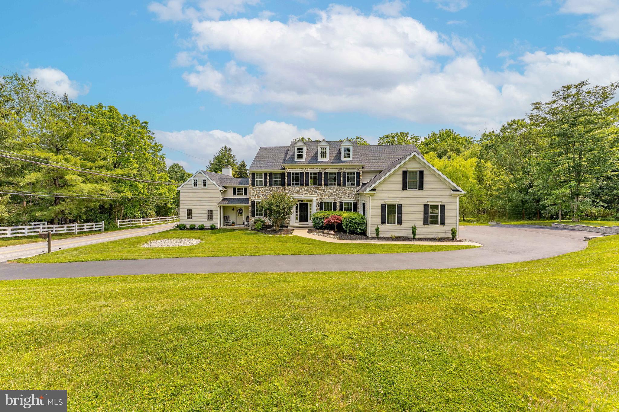 Welcome to 975 S Waterloo Road — a stunning 5-bedroom, 4.5-bathroom custom home set on a beautifully landscaped 1.4-acre lot in the prestigious Waterloo Mills neighborhood of Devon. Set on a picturesque lot, this exquisite residence showcases a blend of HardiePlank and stone exterior, and features a 3-car garage plus a large driveway. A charming breezeway connects the main home with a unique secondary living space, adding versatility to this expansive property. Step inside the grand foyer, where hardwood floors, a sweeping staircase with a chandelier, ceiling lighting, and a large walk-in coat closet set an elegant tone. To the left, French doors open into a bright living room with hardwood floors and front-facing windows. To the right, a formal dining room boasts hardwood flooring, a classic chandelier, and a direct connection to the heart of the home — the gourmet kitchen. Designed for culinary enthusiasts, the kitchen features granite countertops, stainless steel appliances, a spacious island with seating and pendant lighting, and a walk-in pantry. It flows seamlessly into a dramatic two-story breakfast room with balcony overlook, hardwood floors, and open sightlines to both the sunroom and family room. The sunroom offers a tranquil space with triple windows, semi-vaulted ceilings, and direct access to the private back patio and fenced yard. The family room features 9-foot ceilings, hardwood floors, and a gas fireplace — perfect for cozy evenings. A hallway off the kitchen leads to a powder room with pedestal sink, a mudroom with alarm system and side entrance, a laundry room, and a bonus room ideal for a playroom or home office. The breezeway brings you to a separate living area that includes a second living room with exposed wood beams, curved walls, a large wood-burning fireplace, and a closet. Continue on to the home theater, complete with berber carpeting, exposed beams, and elevated recliner seating — a dream for movie lovers. Above this wing, a private guest suite features a sitting room with hardwood floors, wood-beamed ceilings, and barn door to a full en-suite bath with semi-vaulted ceilings and single vanity. The adjacent bedroom includes wood floors, ceiling beams, and ample closet space. Back in the main residence, the second level includes a loft area with carpet and a balcony overlooking the foyer. The second and third bedrooms each offer carpet, ceiling fans, and share a Jack-and-Jill bathroom with tile floors, step-in shower, single vanity, and linen closet. The fourth bedroom includes carpet, a ceiling fan, and easy access to the full hall bath with a tiled tub/shower combo. The primary suite is a true retreat, offering carpet floors, a ceiling fan, a sitting area, and a custom walk-in closet by Closets by Design, complete with skylights and a built-in office nook. The luxurious en-suite bath features tile flooring, a soaking tub, walk-in tile shower with bench, double sink vanity with LED mirror, and a linen closet. Perfectly located near local shopping, restaurants, and grocery stores, this home also enjoys close proximity to Waynesborough Country Club, offering the best of Main Line living. Don’t miss your chance to own this exceptional property — a rare blend of luxury, functionality, and timeless charm!