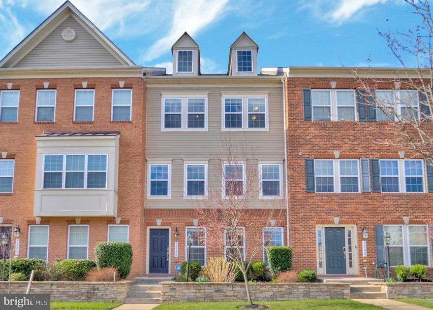 Welcome to 7373 Saint Margarets Blvd, a stunning North-East facing  four-level townhome nestled within the vibrant and amenity-rich Oxford Square community in Howard County. Built by Lennar with a thoughtful blend of innovation, sophistication, and environmental responsibility, this home offers not only beautiful design but also sustainable living at its finest. From the moment you arrive, the curb appeal is undeniable—freshly landscaped grounds, classic vinyl siding, and a charming brick water table set a refined tone before you even step inside. As you enter the sunlit foyer, you're immediately welcomed by brand-new luxury vinyl plank flooring and a soothing, neutral color palette that flows seamlessly throughout the home. Just off the entry, a spacious bedroom with an en-suite bath and walk-in shower offers the perfect retreat for guests, extended family, or a private home office. A built-in mudroom adds both functionality and elegance as it leads to the attached two-car garage—offering everyday ease for busy modern living. Upstairs, the main living area invites you into a space designed for both entertaining and comfort. The gourmet kitchen is the true heart of the home, featuring 42” Snow White cabinetry, gleaming granite countertops, a large center island with seating for five, stainless steel appliances, and a charming coffee nook. A massive butler’s pantry and walk-in storage pantry provide abundant space for every culinary need. The adjacent dining area flows effortlessly into a spacious family room, bathed in natural light and complemented by tasteful window treatments. Step just outside to a private TREX deck—ideal for morning coffee, weekend brunches, or relaxing after a long day. The third level is dedicated to rest and rejuvenation. The elegant owner’s suite, accessed through double doors, offers a peaceful escape with plush new carpet, custom window treatments, a generous walk-in closet, and a spa-inspired en-suite bathroom featuring dual granite vanities, a walk-in shower, and a private water closet. Two additional sun-filled bedrooms, a full bathroom with a tub/shower combination, and a convenient laundry area complete the upper-level living quarters. Ascend one final time to the versatile fourth level, where a bonus fifth bedroom awaits. With its own en-suite bath and a massive walk-in closet, this space is perfect for a guest suite, creative studio, or fitness area. From here, step out onto your private rooftop terrace—an oasis above it all, ideal for yoga at sunrise, evening cocktails, or simply soaking in the view. This home is as efficient as it is elegant, built with advanced construction techniques including state of the art automatic blinds, two 92% high-efficiency gas heating systems, energy-efficient HVAC, Tyvek HomeWrap, dual-pane Low-E windows, premium insulation, and a sealed air barrier for year-round comfort. Additional features like an insulated steel garage door and 35-year architectural shingles speak to the quality and longevity of the build. Located just minutes from major highways with easy access to Baltimore and Washington, D.C., this home also benefits from the community’s exclusive private shuttle to the Dorsey MARC Station—making commuting effortless. Families will appreciate proximity to some of Howard County’s top-rated new schools. Oxford Square enhances everyday living with resort-style amenities including a sparkling swimming pool, state-of-the-art fitness center, basketball courts, playfields, and lush green open spaces. 7373 Saint Margarets Blvd is more than a home—it’s a lifestyle of ease, elegance, and energy-conscious living in one of the area’s most desirable communities. Don’t miss this rare opportunity to make it yours.