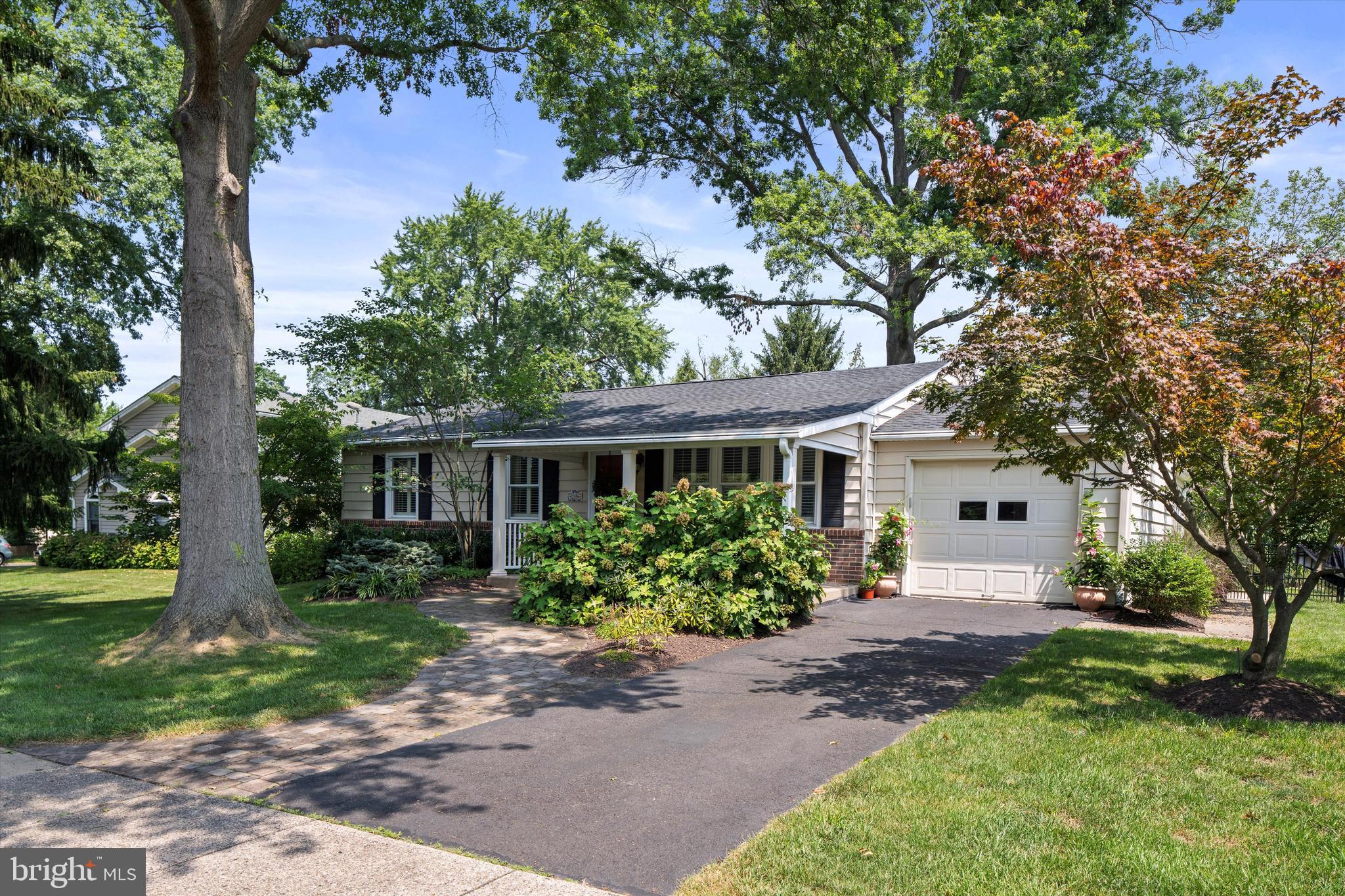Enjoy in-town living in the highly coveted and charming, historic Doylestown Borough! 235 N Franklin Street offers turnkey, one level living with fantastic walkability. Unpack your bags and enjoy all that Doylestown Borough offers – wonderful restaurants, shops, museums, the historic Doylestown County Theater, parks, golf courses and various festivals. Doylestown is steeped in history and the arts. Fonthill Castle, Mercer Museum and Moravian Pottery & Tile Works Museum.
Meander down a lovely paver walkway to the inviting covered front porch of this updated and neat-as-a-pin, ranch style home. Enter the home into the living room with gorgeous hardwood floors and large windows with plantation shutters. The open floorplan flows into the dining area and updated kitchen with custom cabinetry, granite countertops, a breakfast bar, farm sink and recessed lighting. Sliding glass doors from the dining area provide access to your own private, outdoor oasis! The magnificent backyard includes a lovely deck with built-in bench seating, mature landscaping and lovely gardens as well as a newly built, stone outdoor fireplace and flagstone patio. A wonderful place to unwind with a glass of wine and entertain. The home also offers an insulated sunroom with a tiled ceramic floor with heat, ceiling fan and access to the backyard. A great space where you can enjoy tranquil views of the backyard throughout the seasons. The fully fenced backyard provides peace of mind as your 4-legged family members can roam freely. There are 3 bedrooms with hardwood floors and an updated full bathroom. The main level also provides powder room for guests and the garage was upgraded to finished and conditioned living space, offering versatility for parking and much more! The lower level offers a tremendous amount of space for storage and recreational activities. Many updates have been done over the years. Most recently, New Roof 2025, New Furnace 2023, 300 amps. Close in proximity to Doylestown Hospital, Doylestown Airport and nearby major routes, including accessibility to mass transit via Doylestown Train Station and bus stops. Located in the award-winning Central Bucks School District!