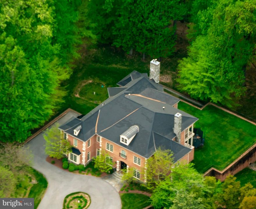 Introducing 7020 Mountain Gate Drive—a distinguished brick residence tucked at the end of a quiet cul-de-sac in the sought-after Bethesda section of Avenel, one of the area’s most prestigious communities. Perfectly situated on a one-acre lot, with sweeping wooded views, this custom-built 2014 home offers an impressive floor plan spanning more than 10,000 square feet. The gourmet kitchen is a true chef’s delight, showcasing an open layout with dual islands, abundant custom wood cabinetry, and rich granite countertops. The kitchen opens seamlessly into the great room, where soaring 21-foot ceilings create a dramatic backdrop. A striking stone-surround gas fireplace serves as the focal point, while walls of windows flood the space with natural light and capture the surrounding scenery. This three-story stone fireplace serves as a striking architectural centerpiece and a magnificent accent to the home. Beyond the great room, a serene office enclosed by windows and enhanced with a tray ceiling offers a bright and quiet retreat for focused work. At the front of the home, just off the main foyer, a secondary office enclosed by French doors provides an equally sophisticated setting—perfect for today’s remote lifestyle. The generously sized dining room, framed with chair-rail molding and illuminated by an elegant chandelier and sconces, provides the perfect setting for hosting large gatherings. An inviting formal living room, centered by a gas fireplace, creates a quiet yet refined lounge, while just beyond, an outdoor terrace offers a fabulous space for open-air relaxation. Everyday convenience is found in the well-appointed mudroom, complete with built-in cabinetry, a washer and dryer, and access to the three-car garage. The upper level boasts a unique floorplan with five spacious sized bedrooms, each featuring its own en-suite bathroom. The primary suite is a true retreat, highlighted by ten-foot ceilings and an expansive layout. It offers an oversized bedroom, a private sitting area with backyard views, a quiet terrace, and a cozy gas fireplace. A grand double-door custom walk-in closet with custom built-in cabinetry throughout, and a luxurious spa-inspired bathroom, complete with a grand walk-in shower, soaking tub and dual vanities, make this space the ultimate sanctuary. Continue down the hallway to discover four additional bedrooms, each with its own walk-in closet. A secondary staircase at the rear of the home provides convenient access to the kitchen and great room below, while also offering a dramatic overhead view of the great room. The lower level of this home is designed for every activity, offering nearly 3,300 square feet of beautifully finished space. The private home theater delivers an authentic cinematic experience, featuring stadium-style reclining seats, full projection, and immersive surround sound—all bringing the magic of the movies to the comfort of your home. Two sizable bedrooms are connected by a Jack-and-Jill bathroom featuring both a tub and shower, while a secondary powder room is available for guests. The lower level opens to a private patio overlooking the flat, expansive lot. 7020 Mountain Gate Drive is an extraordinary offering in the sought-after Avenel community, showcasing a truly distinctive floor plan in one of its most desirable sections. Ideally located with effortless access to Clara Barton Parkway, I-495, and just minutes from Potomac Village and Great Falls National Park, this home combines convenience with unparalleled amenities. Residents of Avenel enjoy exclusive access to community pools, parks, and tennis/pickleball courts—all included in the monthly association fee. Even better, exterior landscaping is maintained by the HOA, allowing for worry-free living. With its rare blend of features, amenities, and location, opportunities like this are few and far between—do not miss this premier residence.