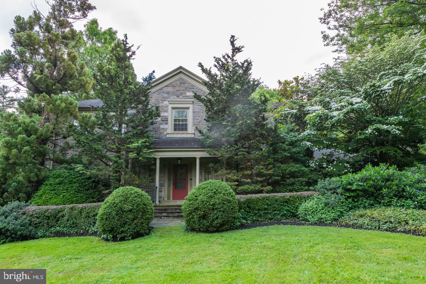 Beautiful center hall stone colonial has all the charm and character you would expect to find in this classic home. The open foyer leads you to the spacious living room, perfect for entertaining, with built in bookcases, shelving on either side of the fireplace and a bay window that allows the natural light in. The center island kitchen, with custom cabinets and stone counters, provides seating and space for an informal gathering or through the French doors to the adjoining formal dining room with its unique see-through glass cabinet. The dining room is open to the atrium room with gas fireplace, cabinets, floor to ceiling windows and two sets of doors leading to the patio and back yard. The back hallway, with the original stone exterior wall, leads to another sunroom off the patio.
The second floor Main Suite has a walk-in closet, office, and additional closet. The ensuite bathroom offers a jetted tub and stall shower. Also included is a multipurpose room that was used as a fitness room overlooking the rear yard. There are three more spacious bedrooms and two Jack and Jill baths. The hall off the kitchen on the main floor has two additional bedrooms and a full bath. The third floor is a walk-up attic allowing for additional storage. The partially finished lower level, with wood beamed ceiling, offers additional 1,070 sf. of living space, a stone surround wood fireplace, bay window, outside entrance and bar area.
All this is set on 1.24 acres of lush foliage, on a quiet street, creates a tranquil setting. It is a leisurely walk to St. David’s or Wayne, the train to downtown and minutes from Rt. 476. Do not miss this opportunity to put your finishing touches and make this your home.